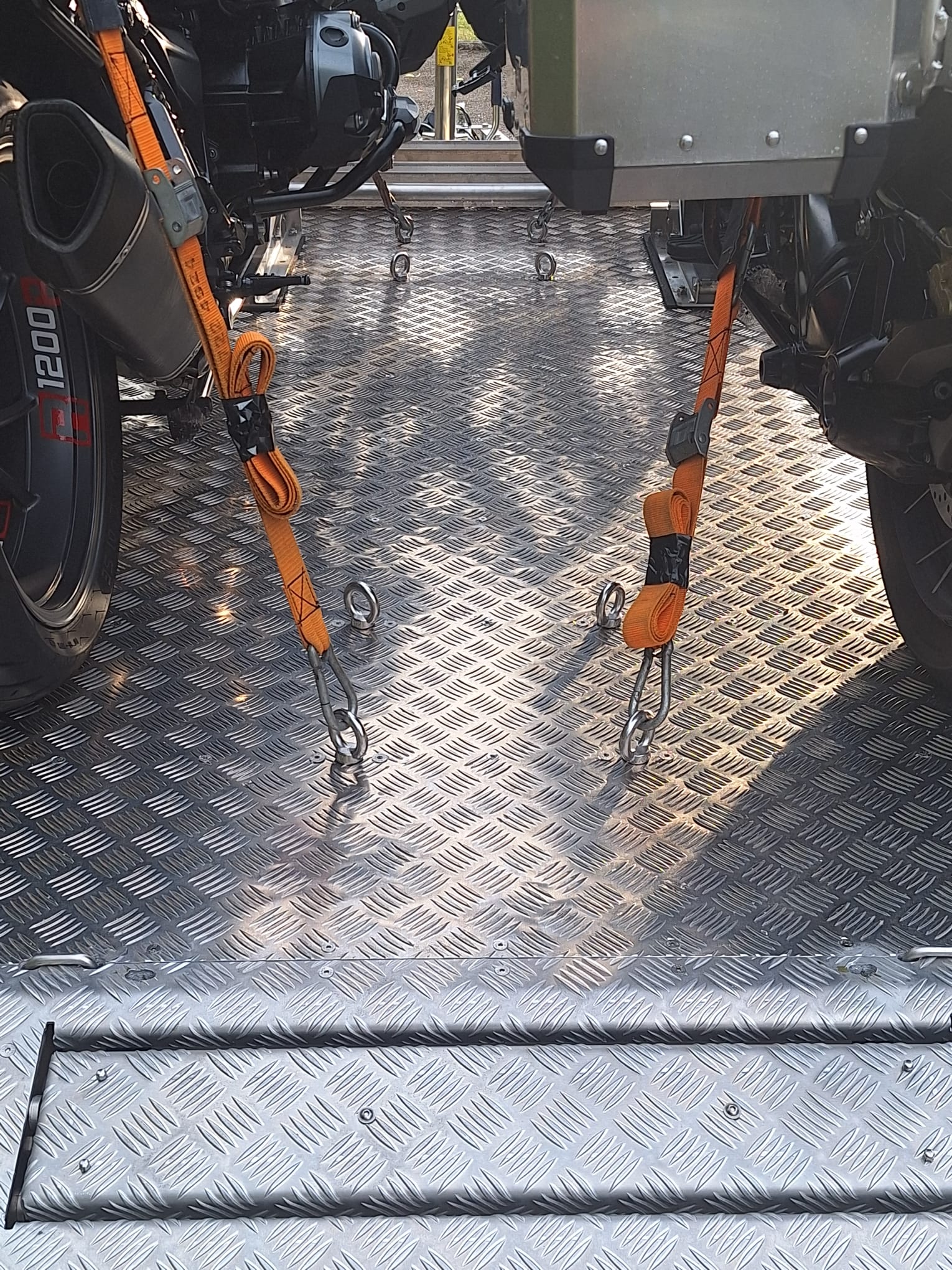 Aluminium Absenkanhänger zwei Motorrädern beladen. Detailaufnahme des Zurrgurts am Anhänger