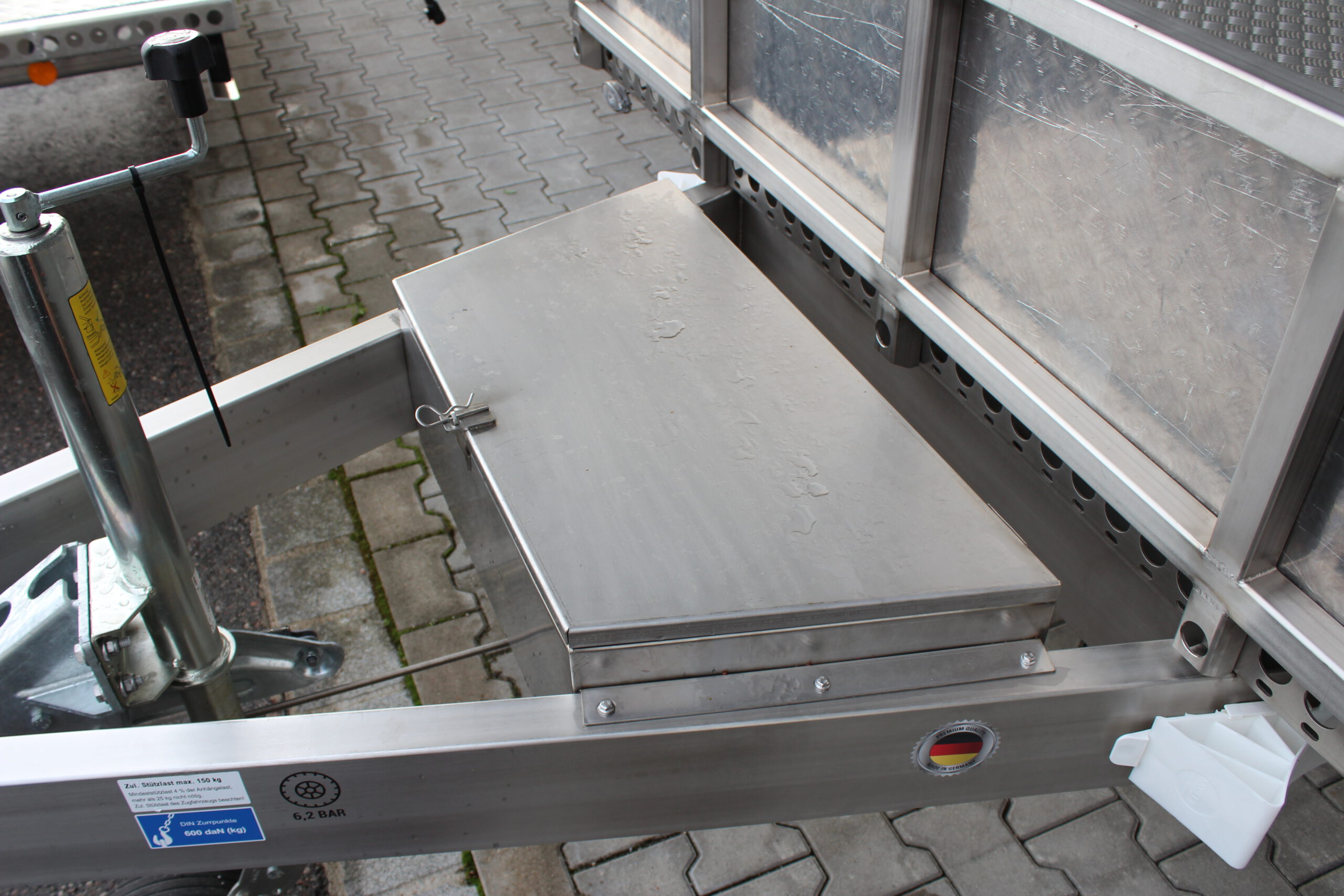 Silberne Edelstahl Staubox mit Deckel oben, in einer Zugdeichsel eines Anhängers verbaut