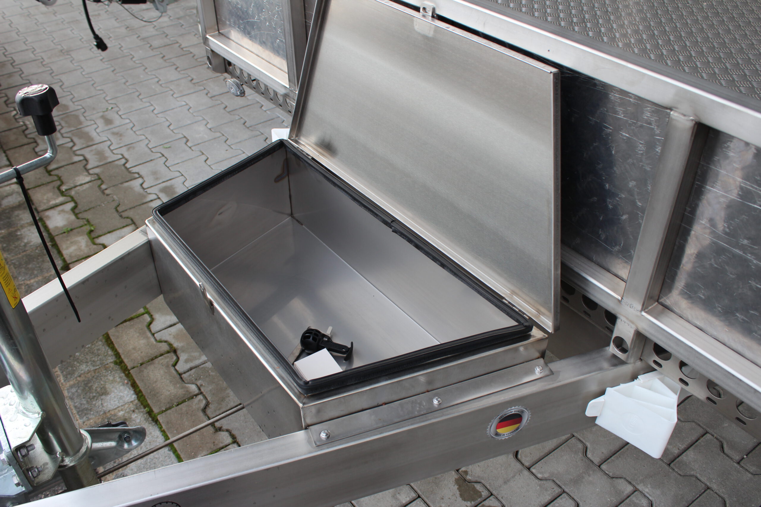 Silberne Edelstahl Staubox mit Deckel oben, in einer Zugdeichsel eines Anhängers verbaut