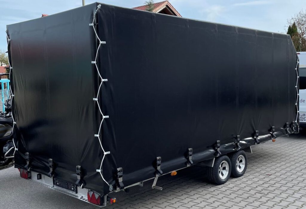 Anhänger mit Hochplane in schwarz mit Motorrad im Hof