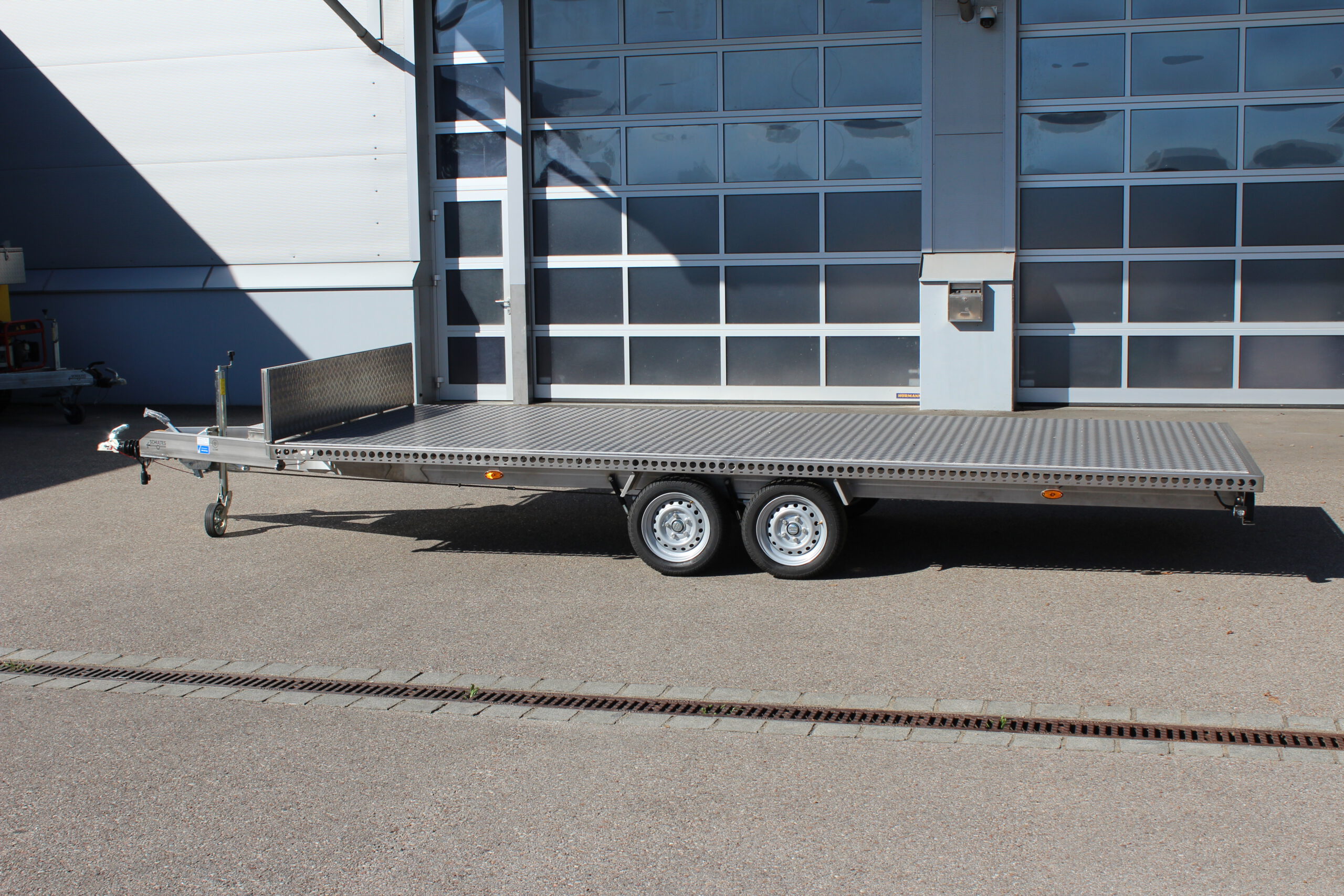 Edelstahl Anhänger 5,10m x 2,10m mit Aluminium Bodenplatte und Stirnwand. Silber, 2-Achser vor einer Halle auf einem Hof