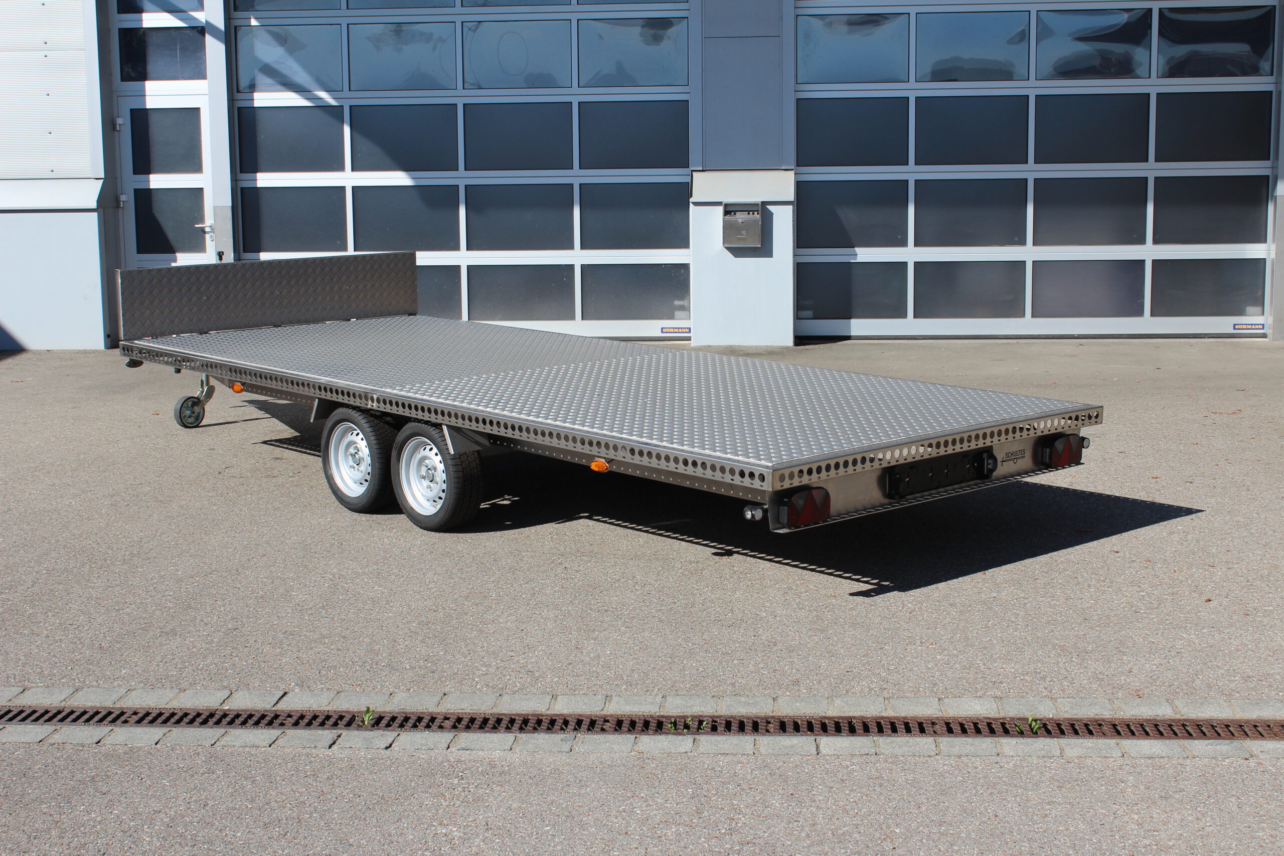 Edelstahl Anhänger 5,10m x 2,10m mit Aluminium Bodenplatte und Stirnwand. Silber, 2-Achser vor einer Halle auf einem Hof