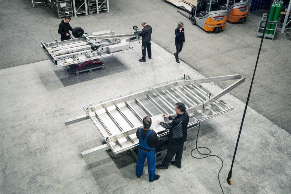 Mehrere Personen in einer Montagehalle für Anhänger