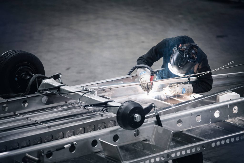 Person schweißt Rahmen eines Anhängers