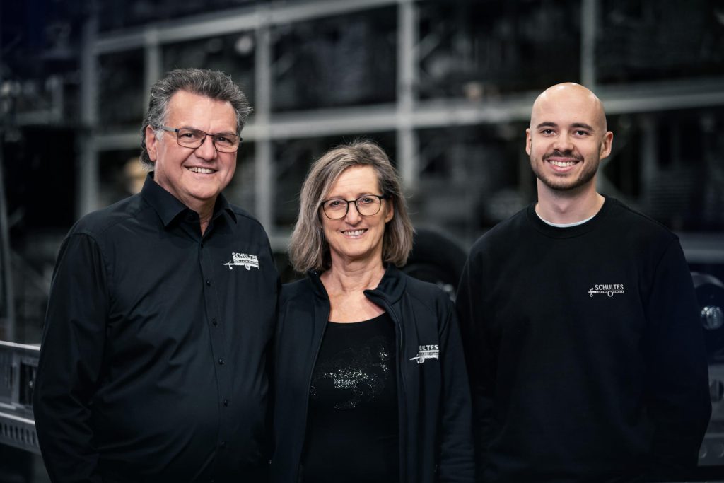 Portrait von drei Personen vor einem verschwommenen Regal