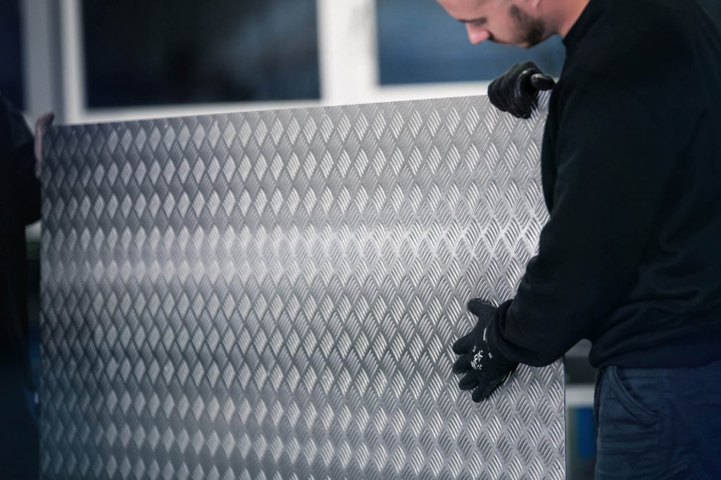 Person hält Hand an eine stehende Aluminium Riffelblechplatte