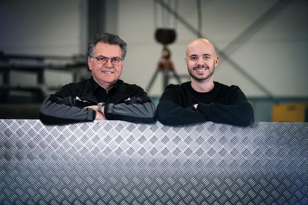 Zwei Personen lehnen auf einer Aluminium Riffelblechplatte