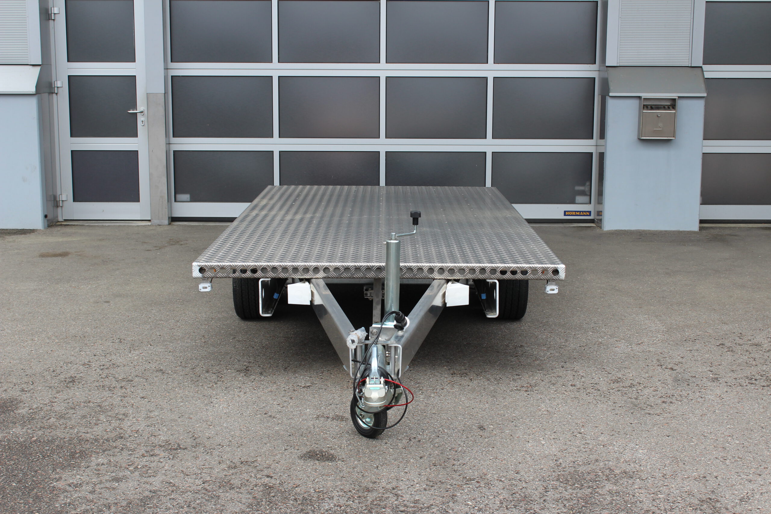 Aluminium Plattformanhänger Tandem - Ansicht von vorne - vor Hallentor