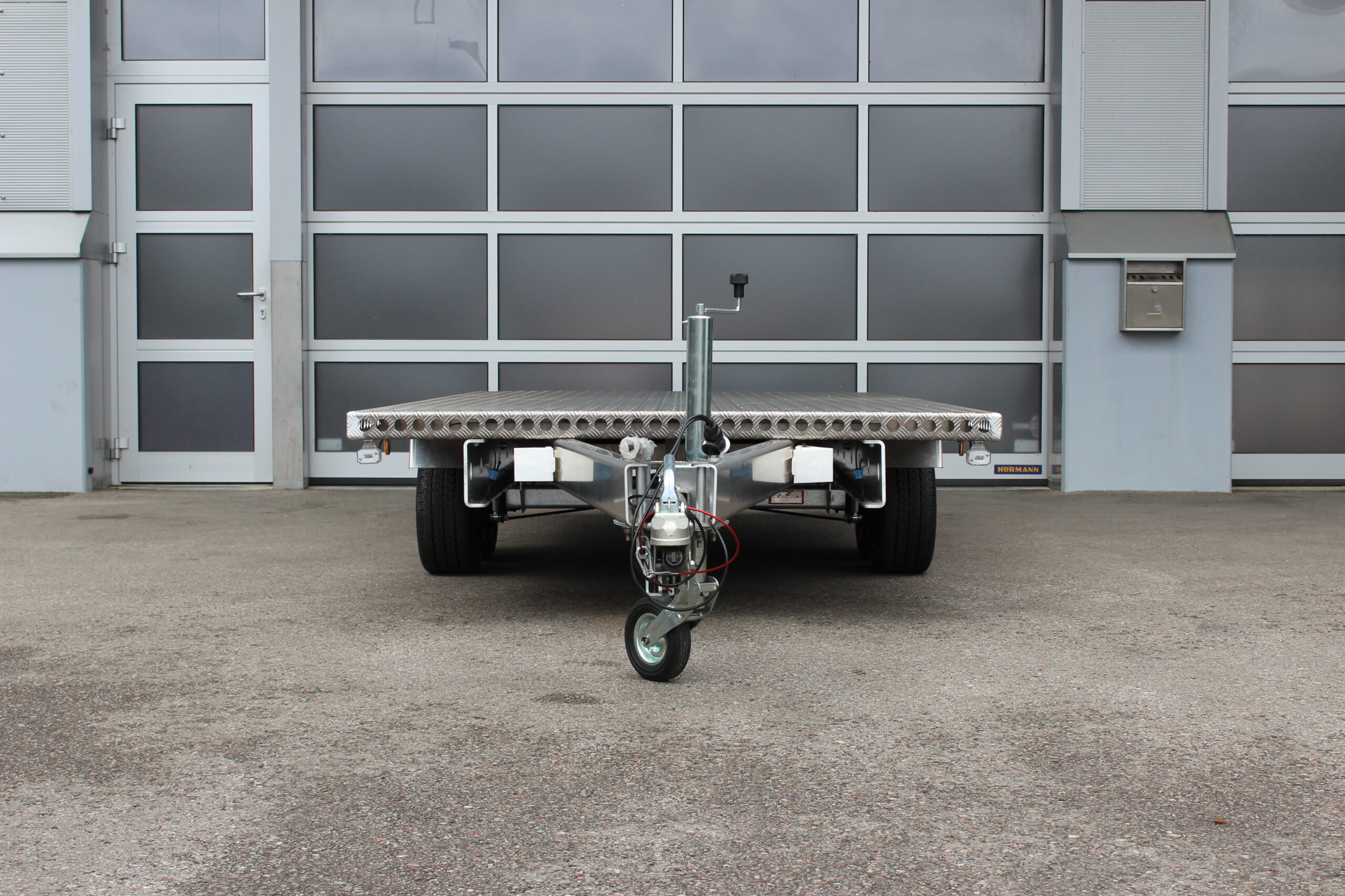Aluminium Plattformanhänger Tandem - Ansicht von vorne - vor Hallentor