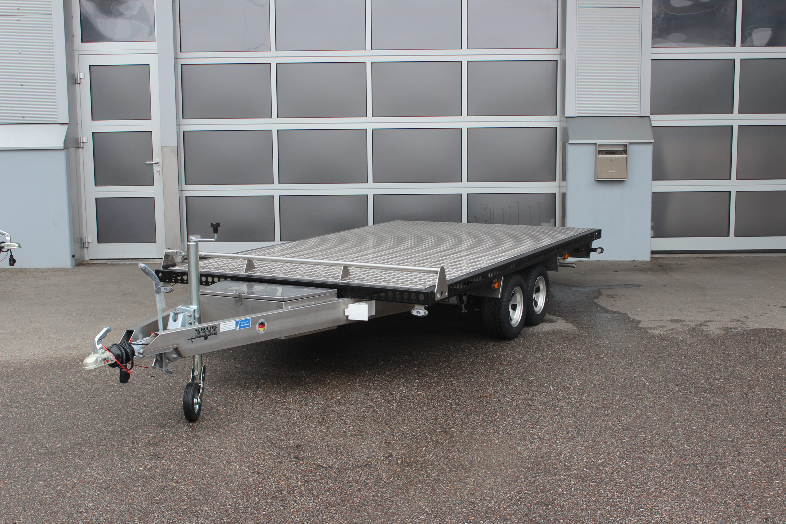 UA350 Edelstahl Anhänger Tandem mit Alufelgen, Rand umlaufend schwarz lackiert, Bodenplatte silber, vor einer Halle
