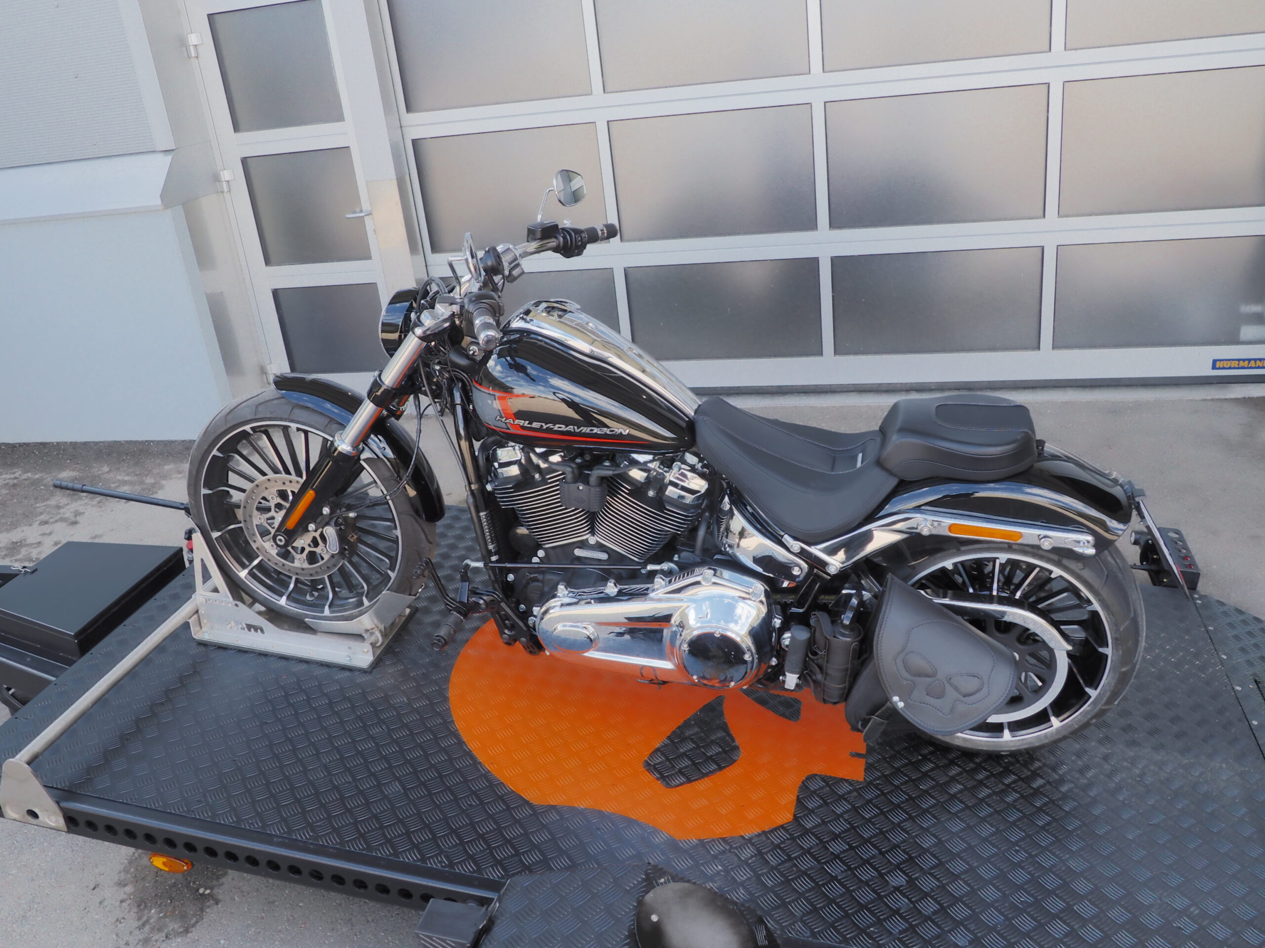 Absenkanhänger schwarz mit Totenkopf. Darauf eine Harley Davidson - vor einem Hallentor