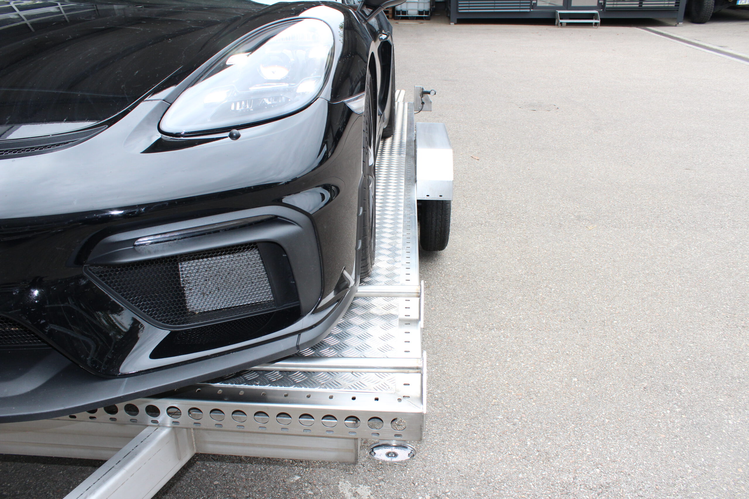 Auto auf Tieflader Anhänger - Detailaufnahme des Abstands vom Auto zum Kotflügel des Anhängers - in einem Hof
