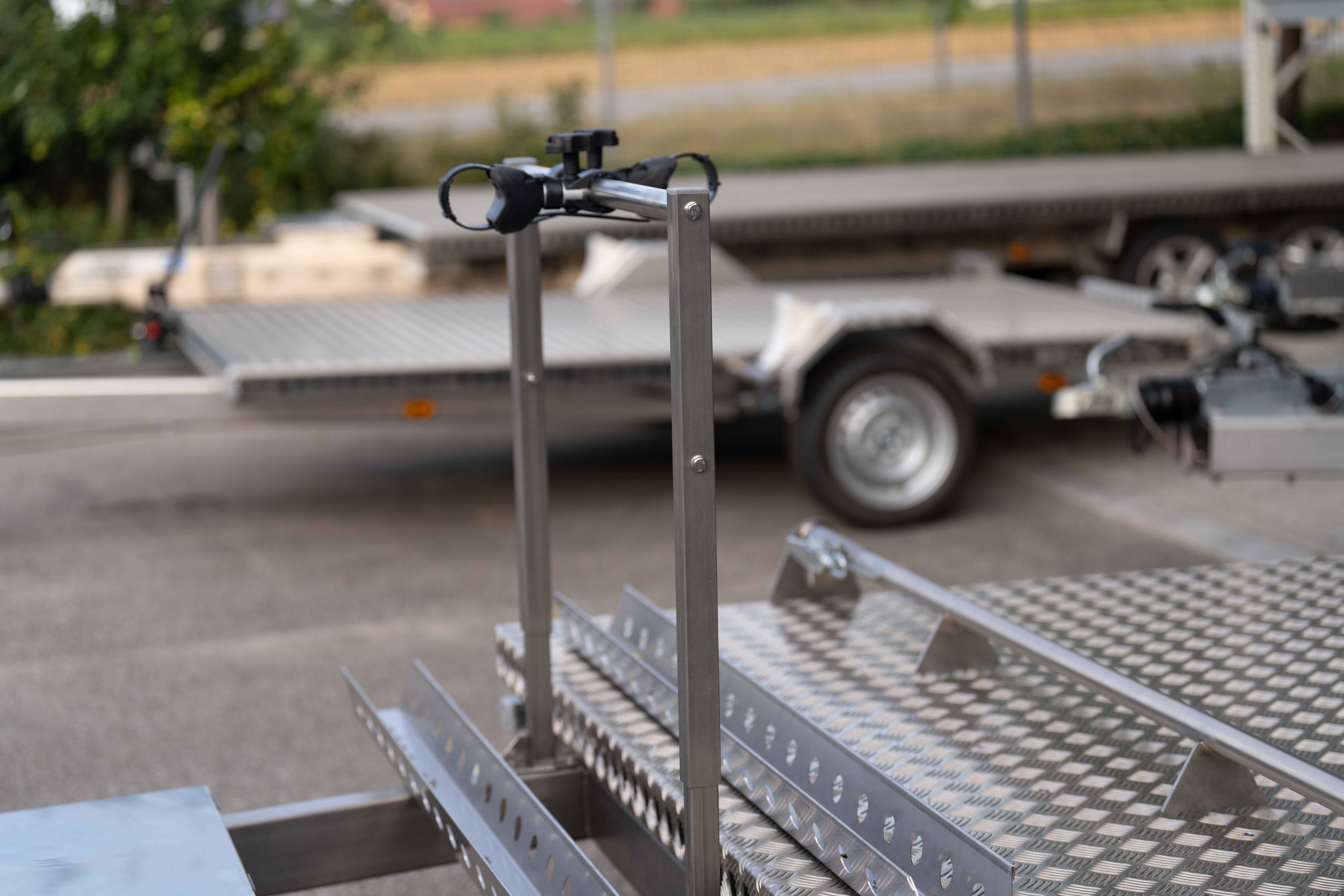 Fahrradträger für 2 E-Bikes an einem Anhänger auf und vor der Plattform in einem Hof