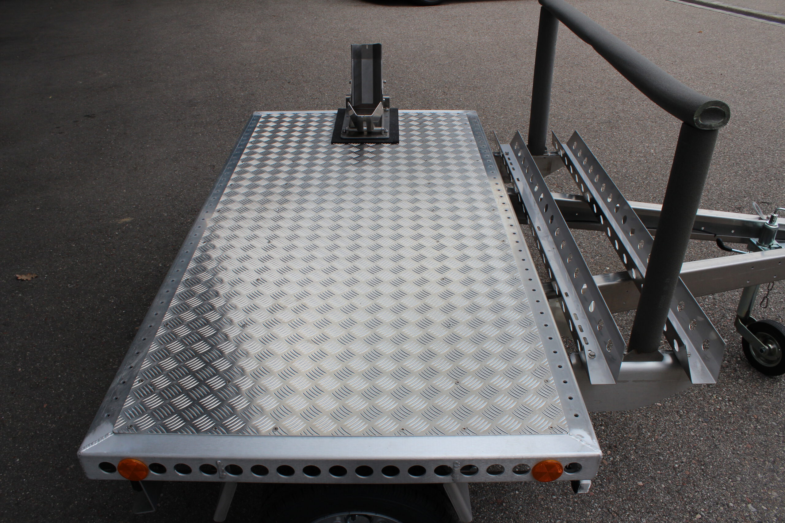 Kleiner Aluminium Plattformanhänger mit Radwippe und Fahrradträger in einem Hof