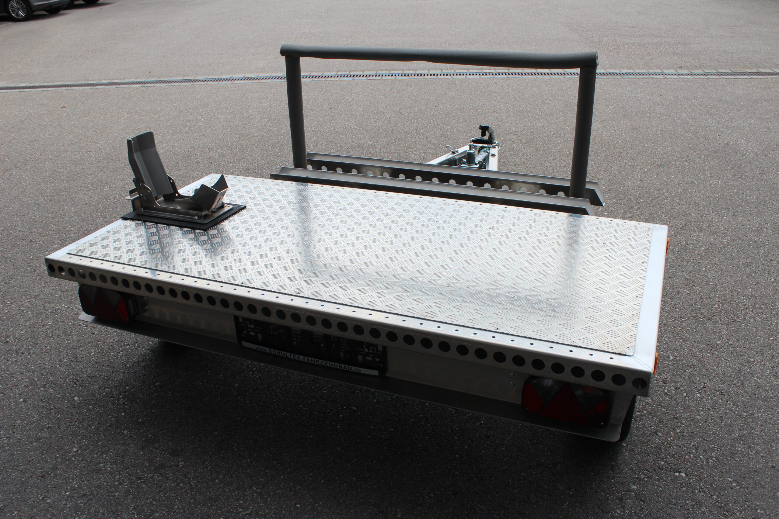 Kleiner Aluminium Plattformanhänger mit Radwippe und Fahrradträger in einem Hof