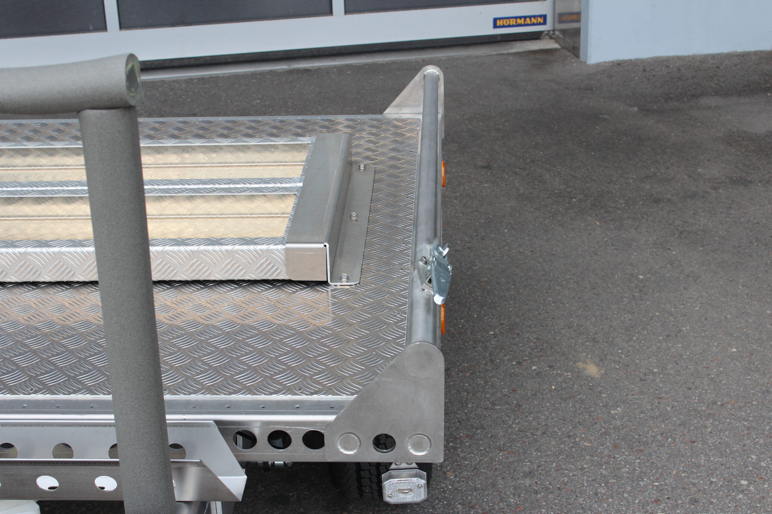 Kleiner Aluminium Plattformanhänger mit zwei Auffahrrampen und Fahrradträger - Detailaufnahme der Anfahrstange von vorne