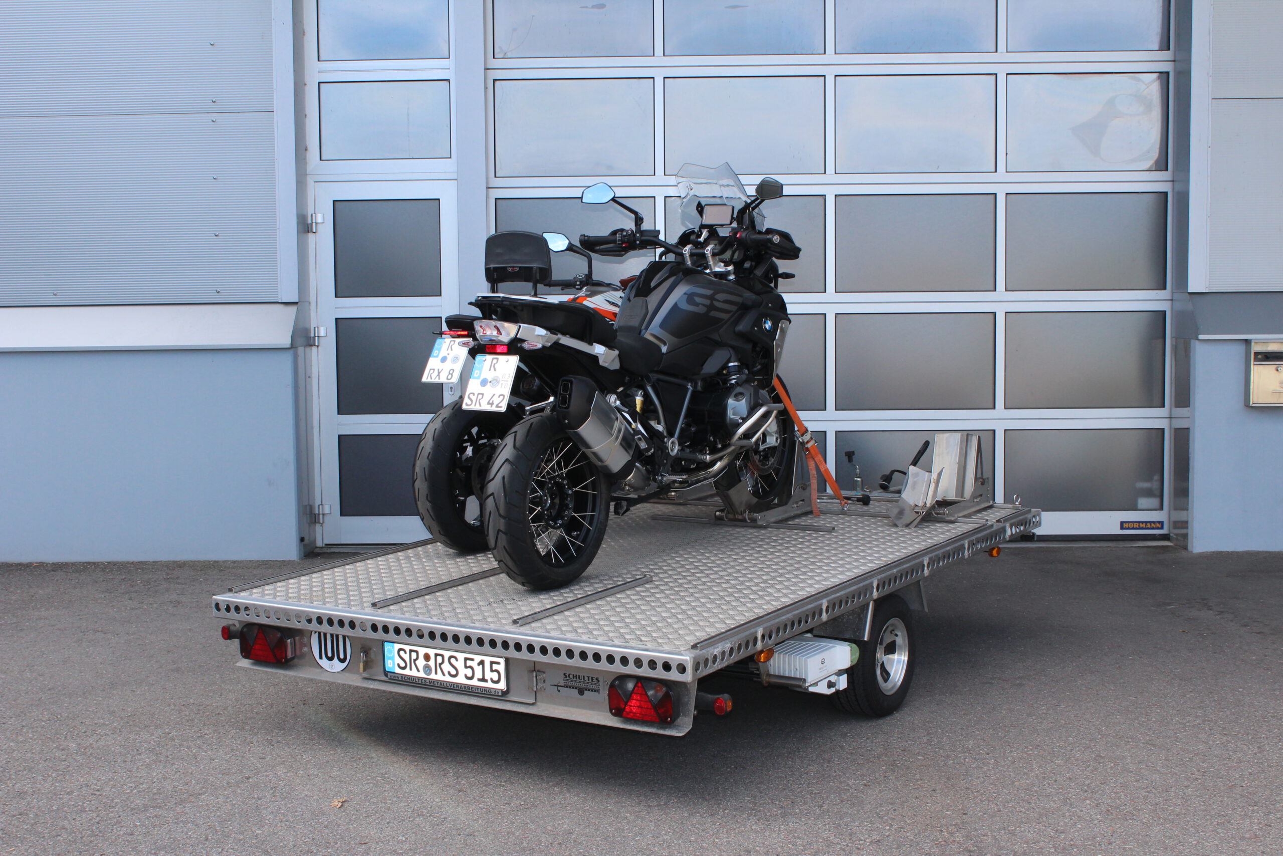 Aluminium Anhänger für drei Motorräder beladen mit BMW GS und KTM Duke vor einem Garagentor - Ansicht von hinten