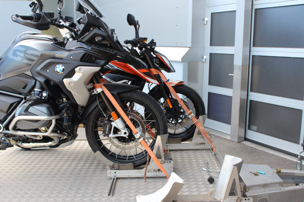 Aluminium Anhänger für drei Motorräder beladen mit BMW GS und KTM Duke vor einem Garagentor - Nahaufnahme von der Seite