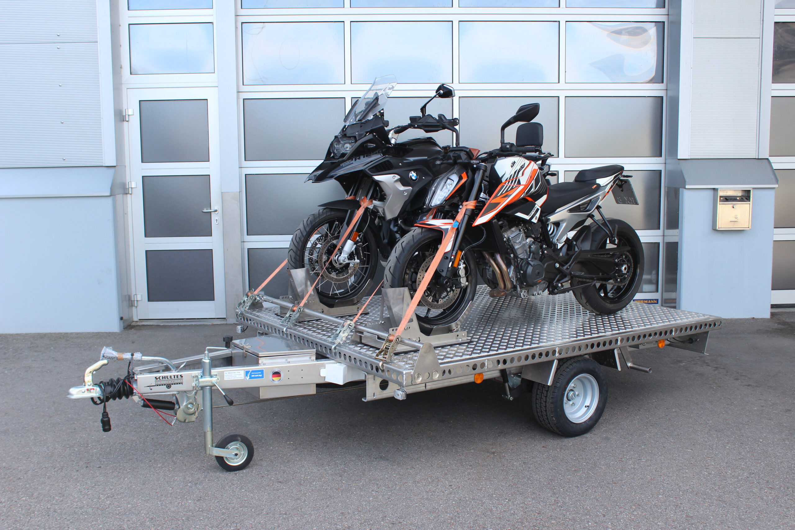 Aluminium Anhänger beladen mit BMW GS und KTM Duke vor einem Garagentor - Ansicht von der Seite