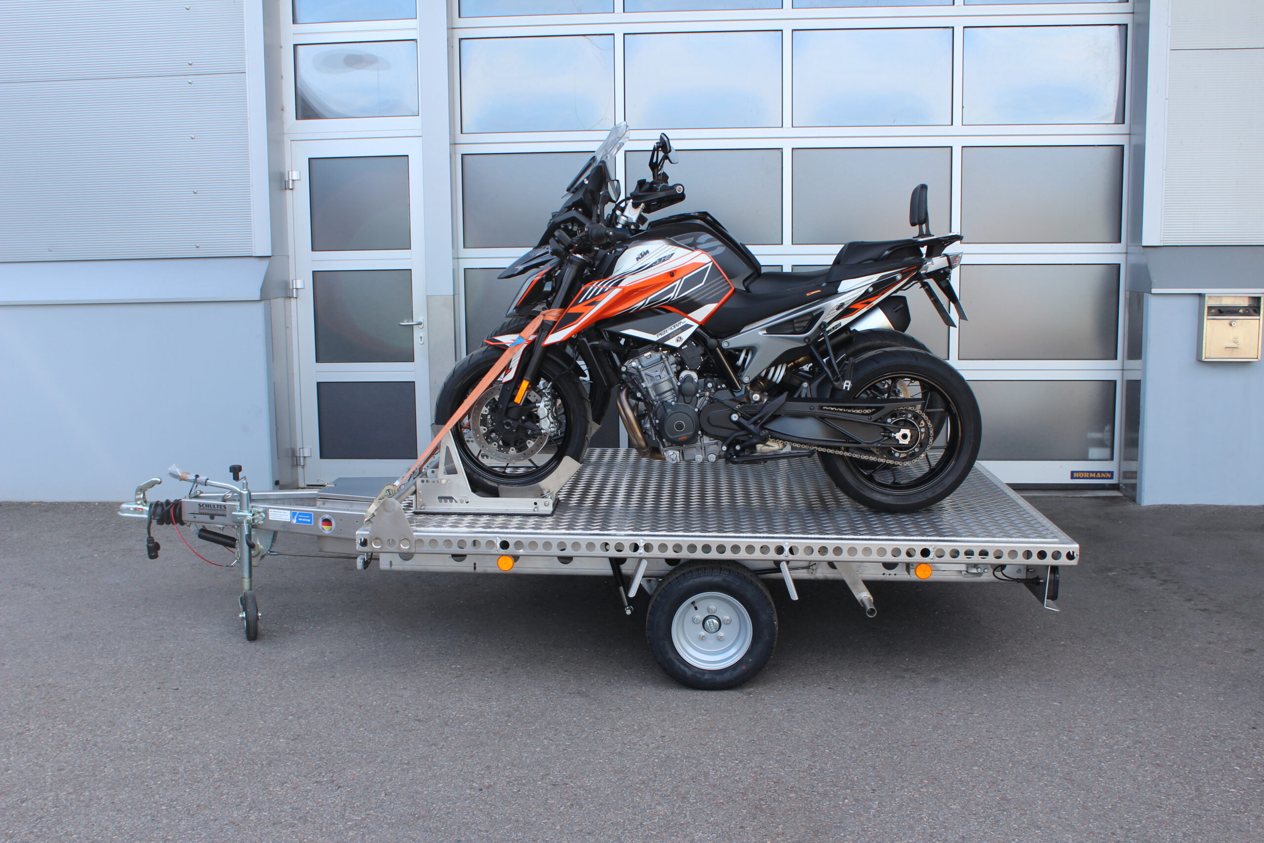 Aluminium Anhänger beladen mit BMW GS und KTM Duke vor einem Garagentor - Ansicht von der Seite