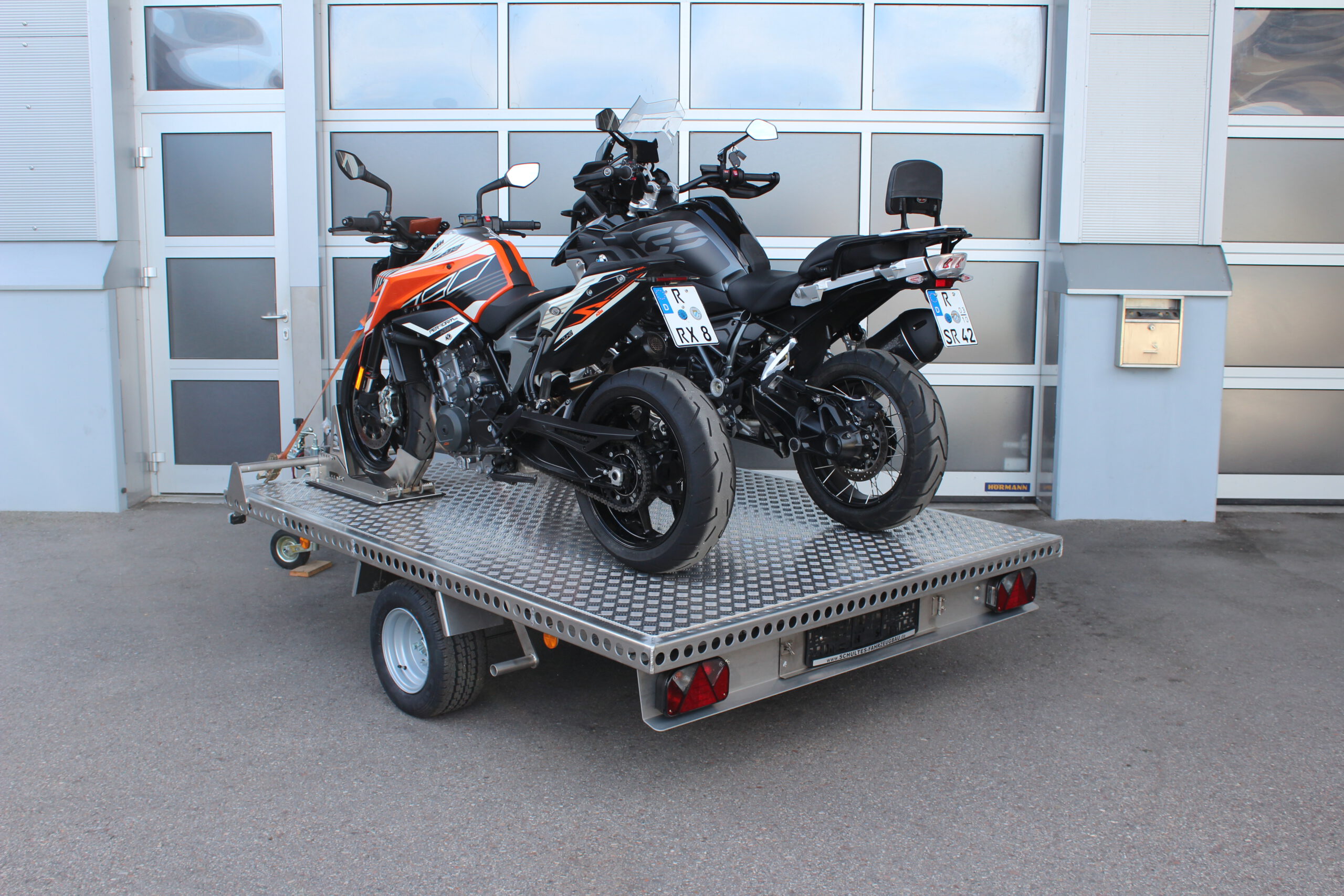 Aluminium Anhänger beladen mit BMW GS und KTM Duke vor einem Garagentor - Ansicht von Hinten