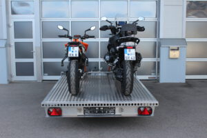 Aluminium Anhänger beladen mit BMW GS und KTM Duke vor einem Garagentor - Ansicht von Hinten