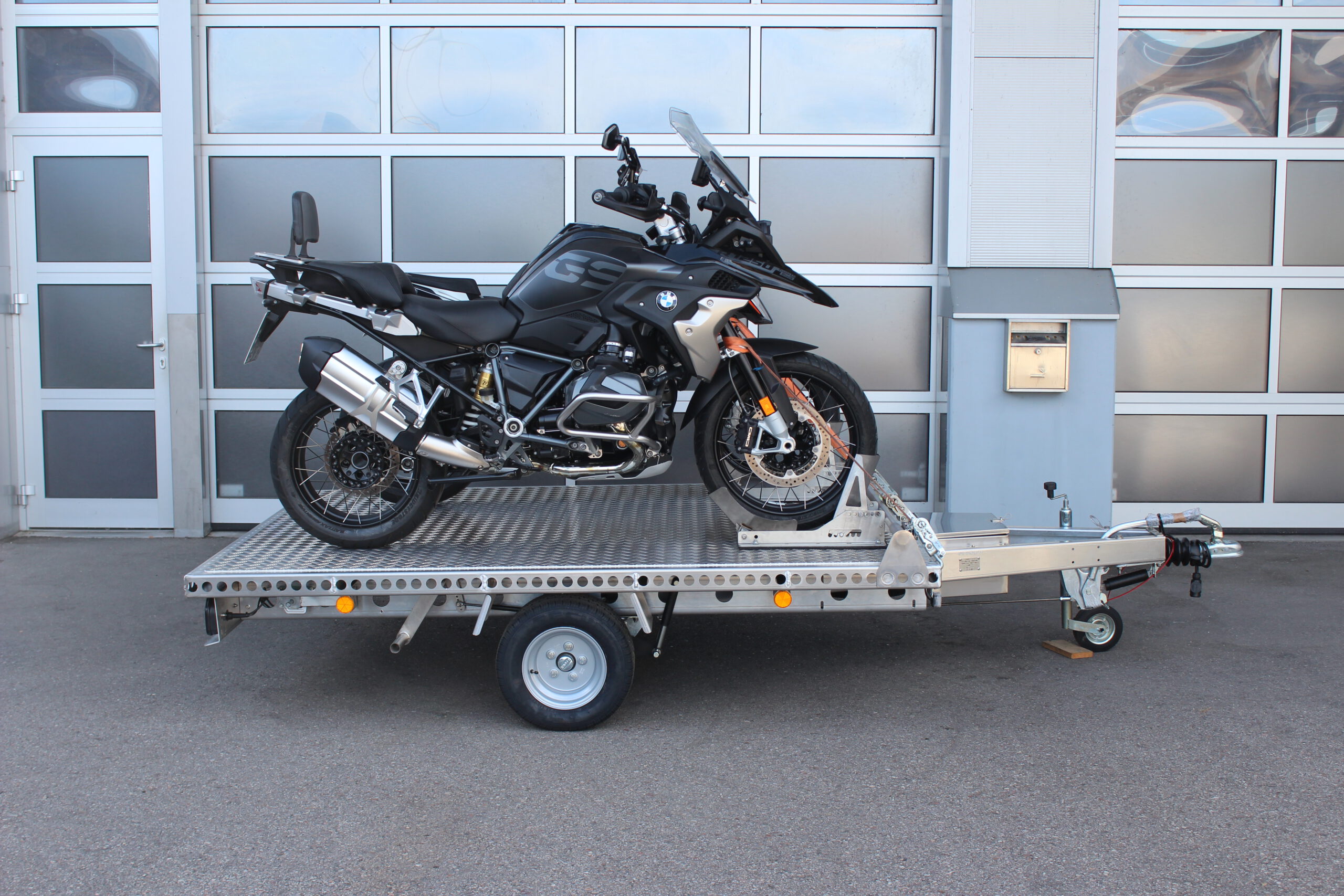 Aluminium Anhänger beladen mit BMW GS und KTM Duke vor einem Garagentor - Ansicht von der Seite
