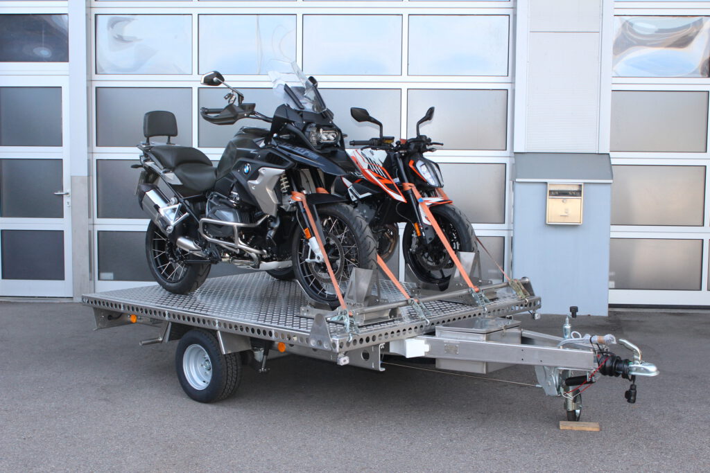 Aluminium Anhänger beladen mit BMW GS und KTM Duke vor einem Garagentor - Ansicht von der Seite