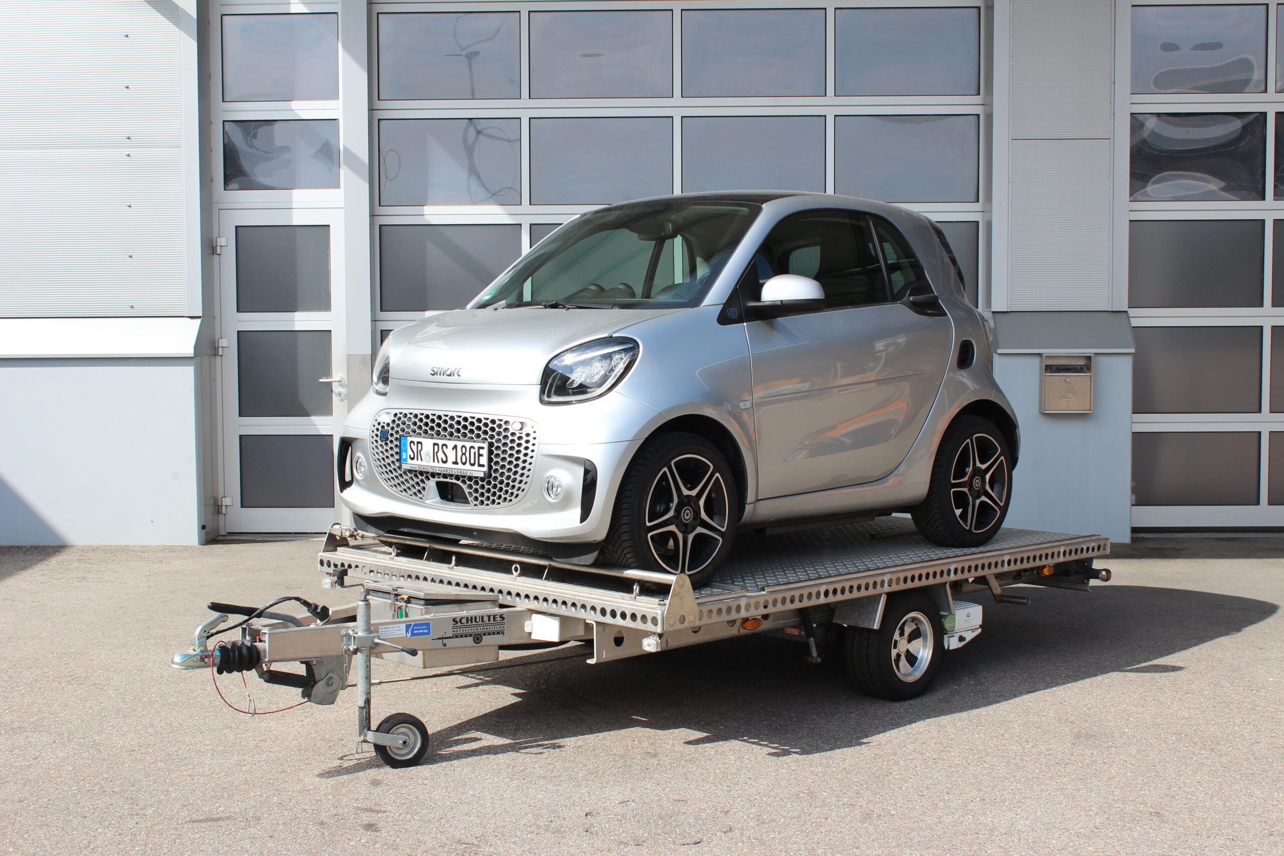 Smart auf Anhänger mit Mover - Vor geschlossenem Hallentor - Ansicht von vorne