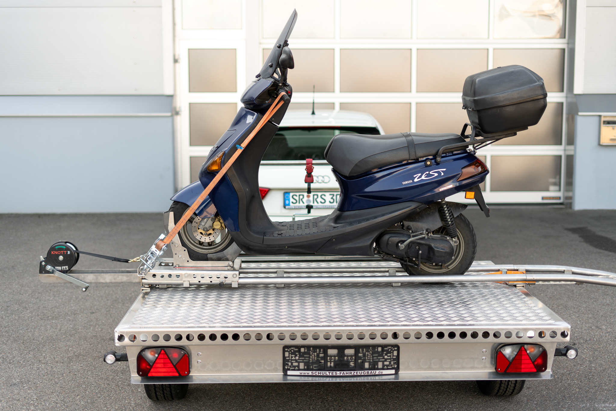 Motorrad Verladesystem - Roller auf dem Anhänger - Vor einer Halle - Seitenansicht