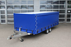 Edelstahl Plattformanhänger mich Hochplane in blau, Seitlich mit Schiebeplane, in einem Hof vor einer Halle