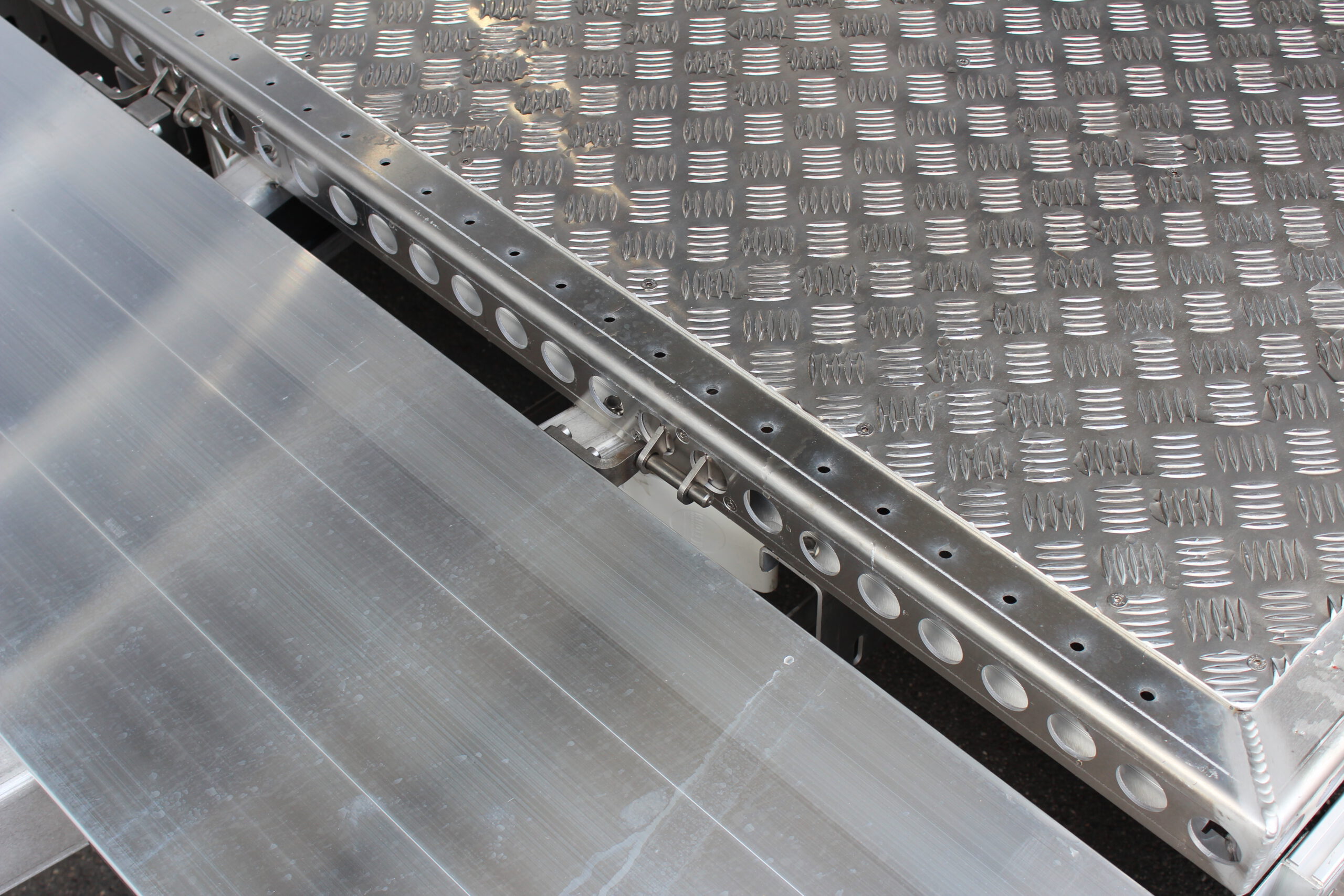 Aluminium Plattformanhänger mit Aluminium Bordwänden vor einem Hallentor