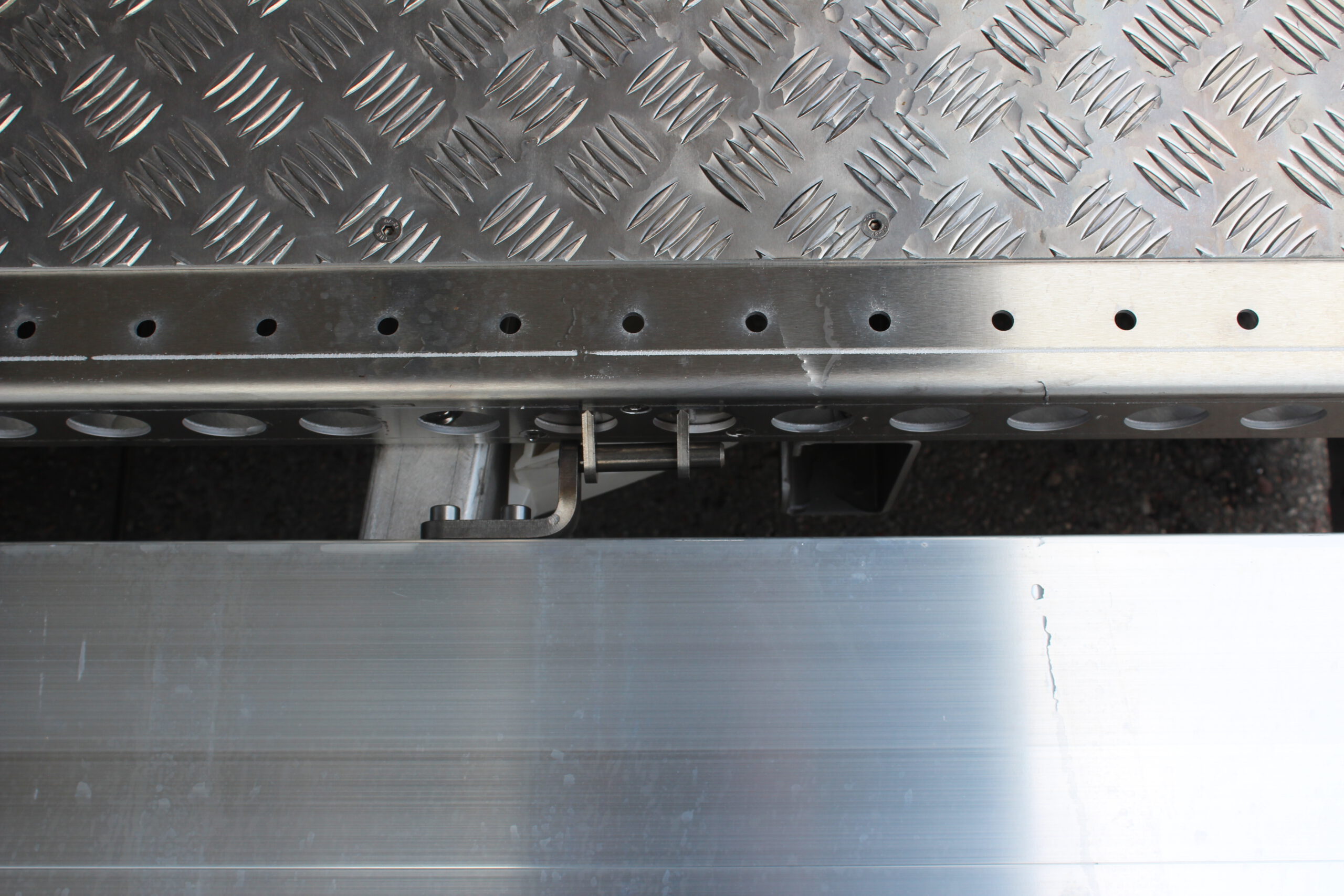 Aluminium Plattformanhänger mit Aluminium Bordwänden vor einem Hallentor