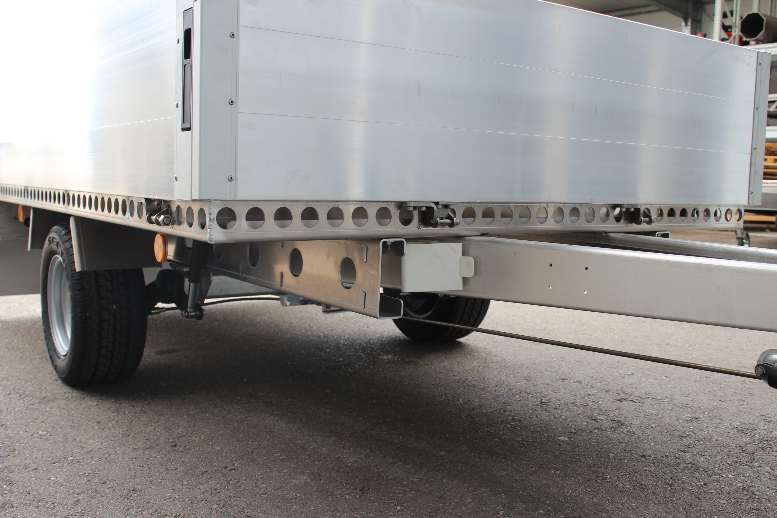 Aluminium Plattformanhänger mit Aluminium Bordwänden vor einem Hallentor