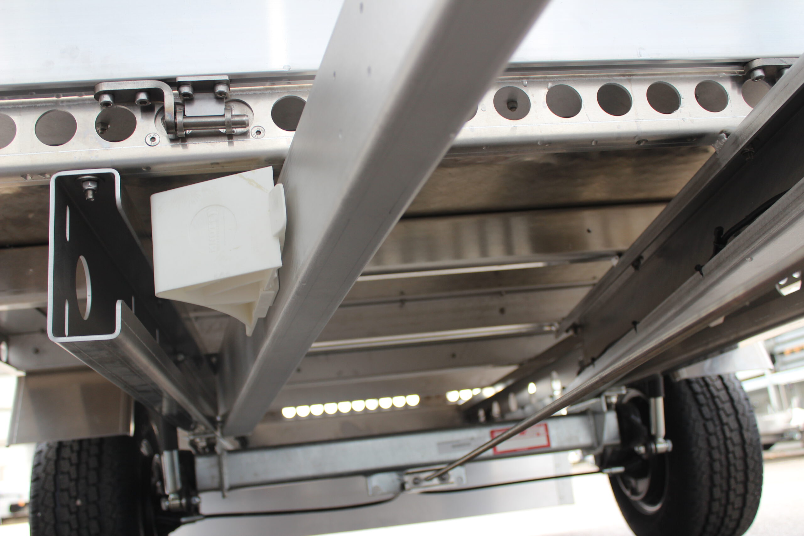 Aluminium Plattformanhänger mit Aluminium Bordwänden vor einem Hallentor