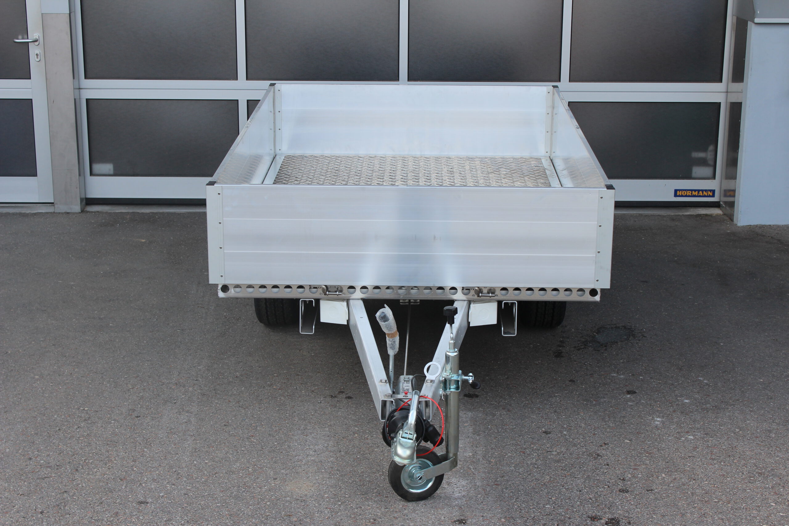 Aluminium Plattformanhänger mit Aluminium Bordwänden vor einem Hallentor