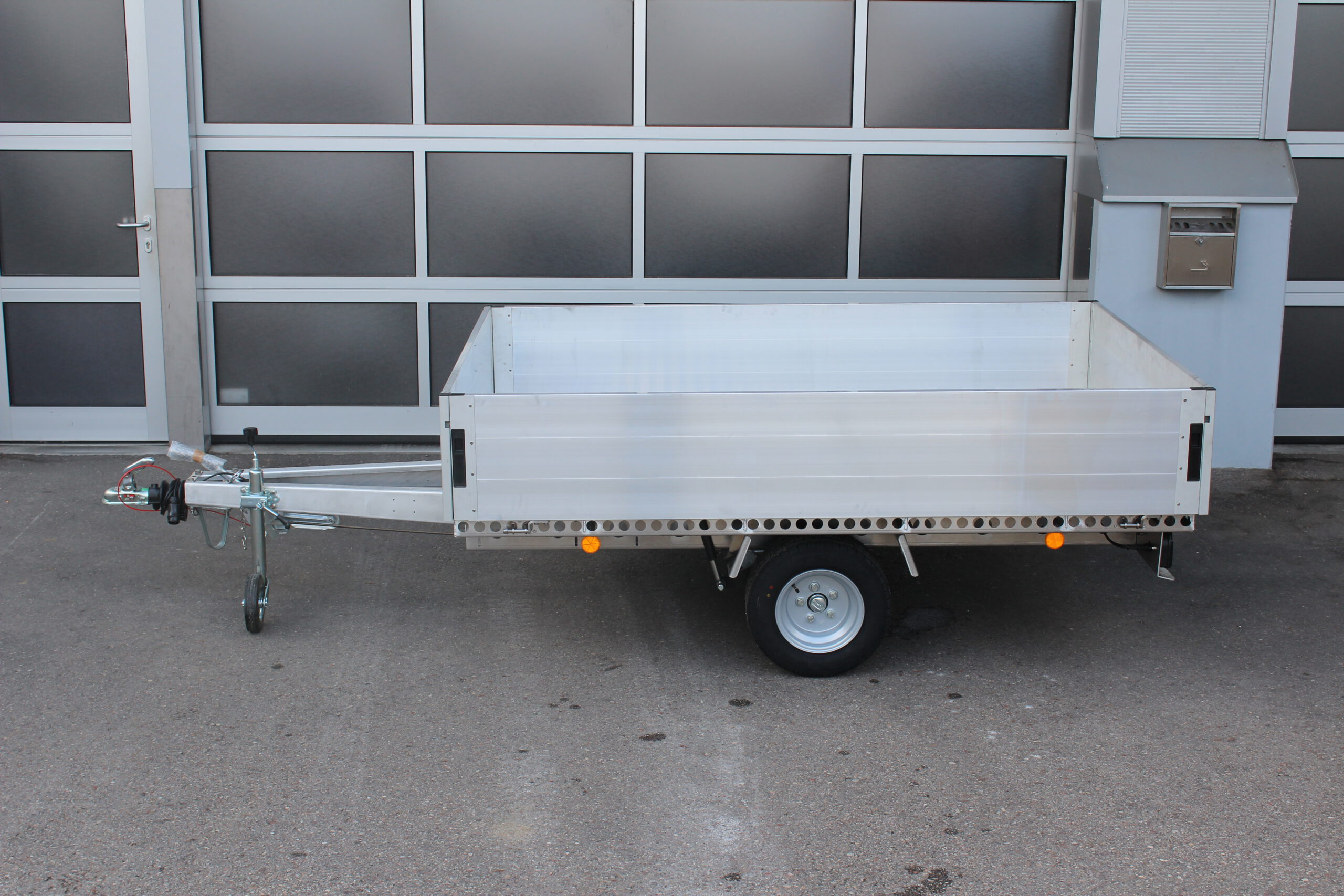 Aluminium Plattformanhänger mit Aluminium Bordwänden vor einem Hallentor