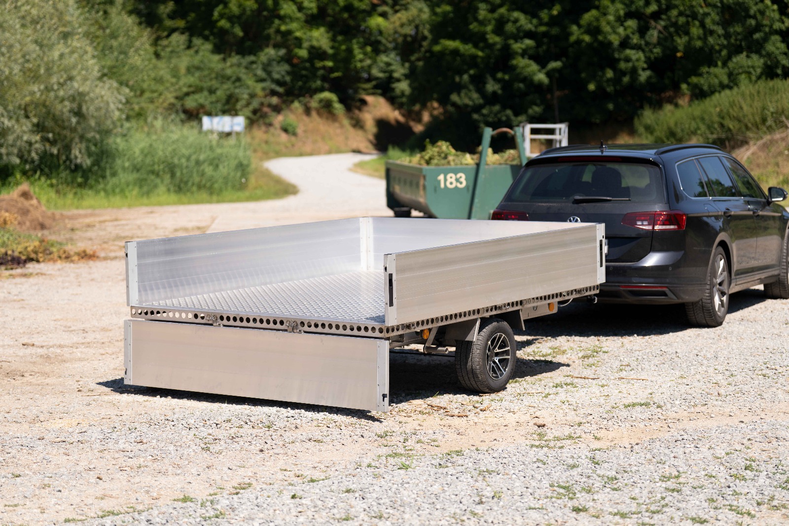 Silberner Anhänger mit Bordwänden vor einem Grüngut Abladeplatz