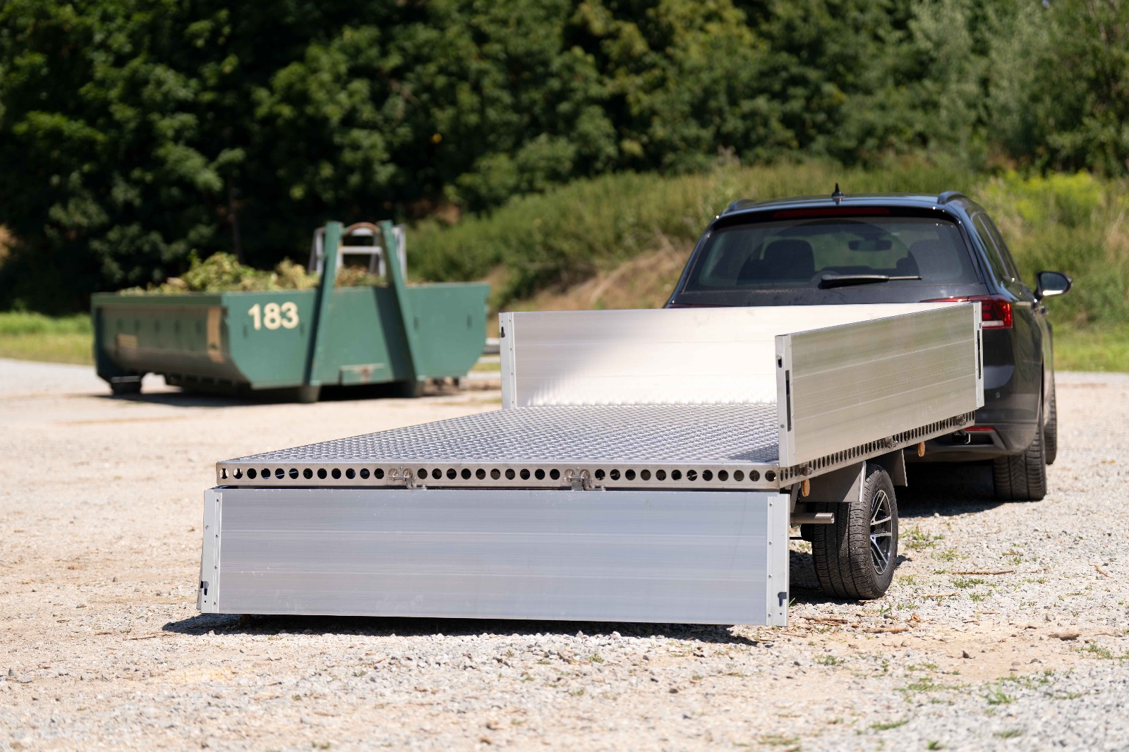 Silberner Anhänger mit Bordwänden vor einem Grüngut Abladeplatz