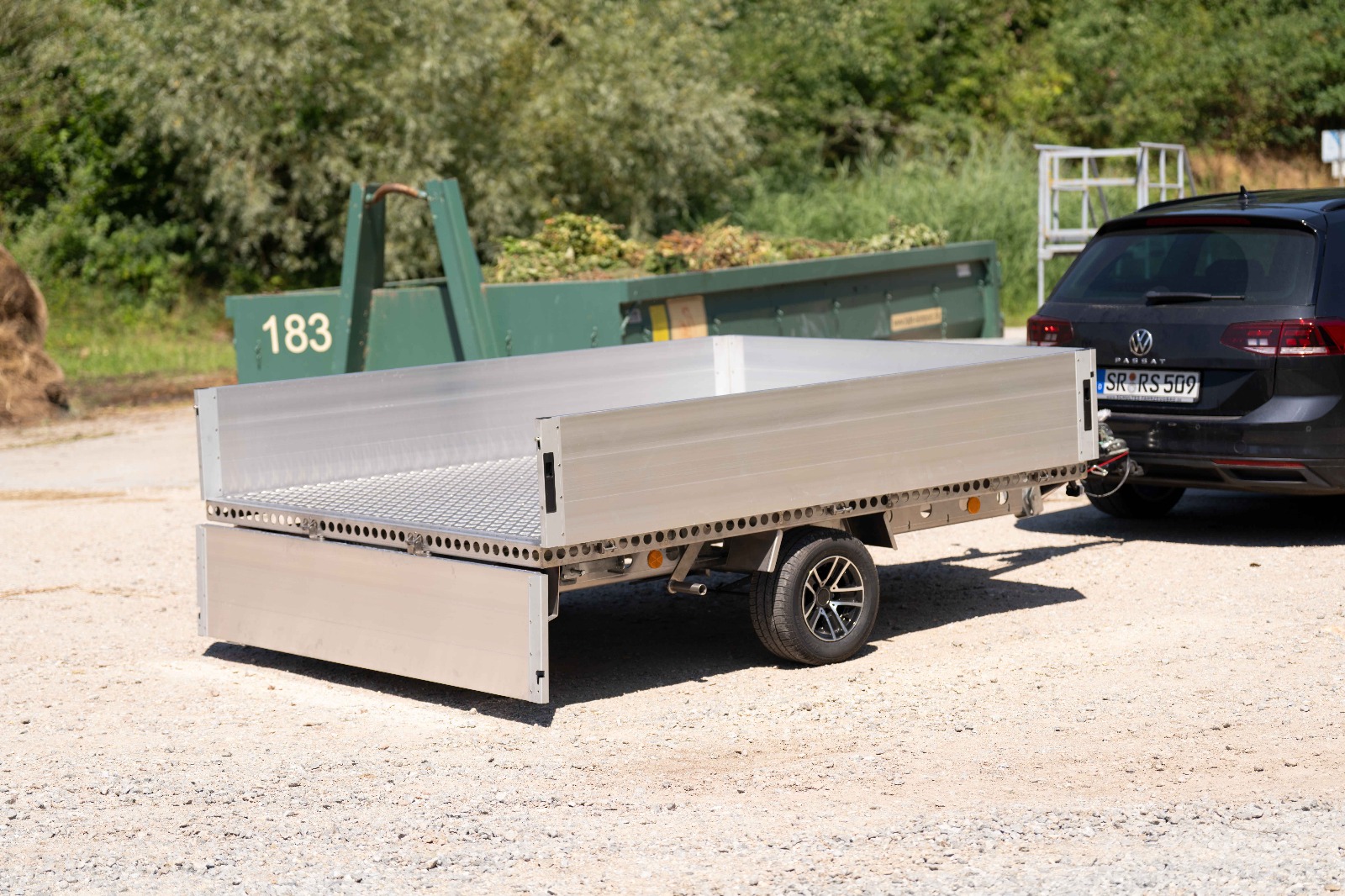 Silberner Anhänger mit Bordwänden vor einem Grüngut Abladeplatz