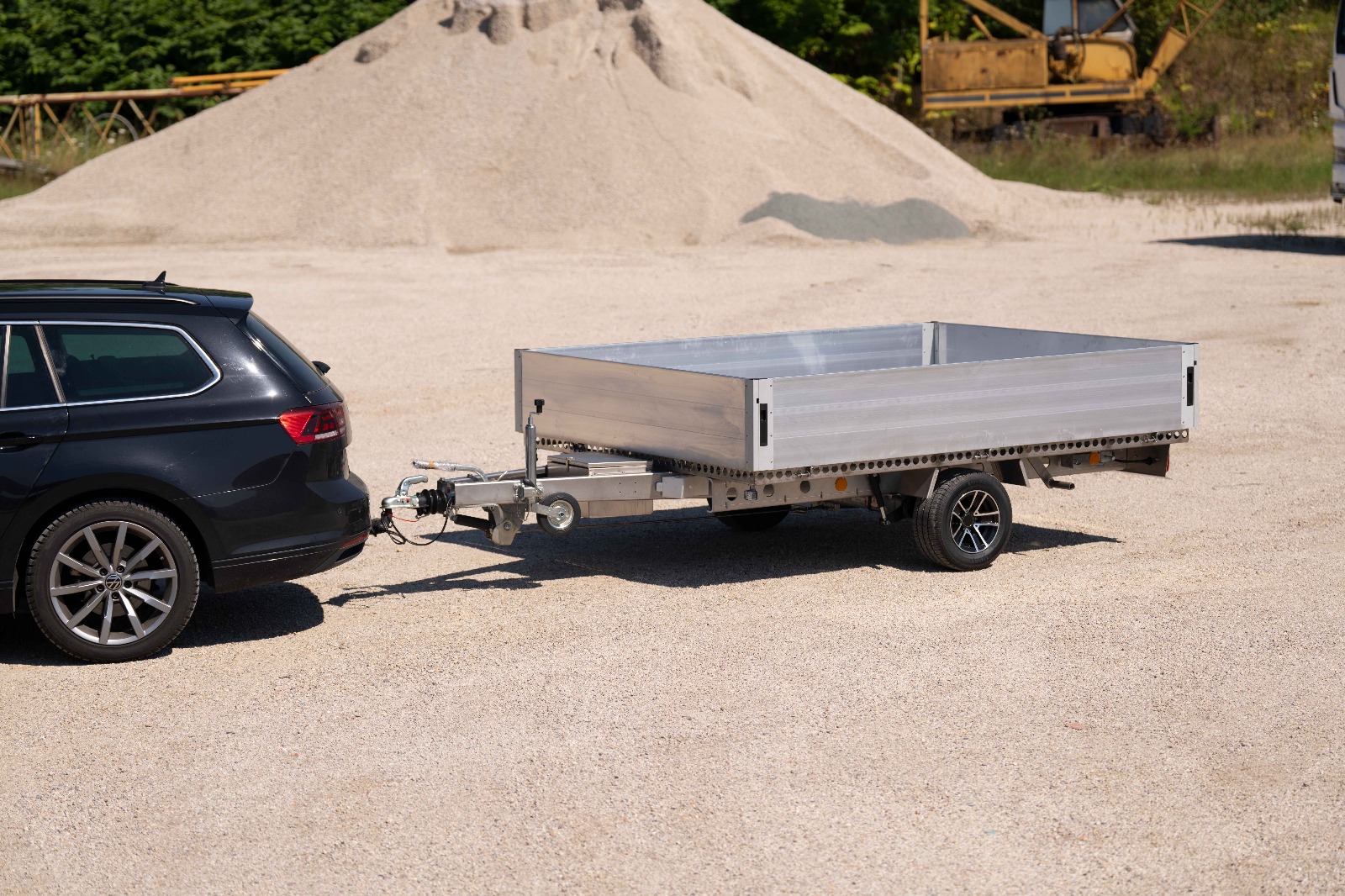 Silberner Anhänger mit Bordwänden vor einem Sandhaufen