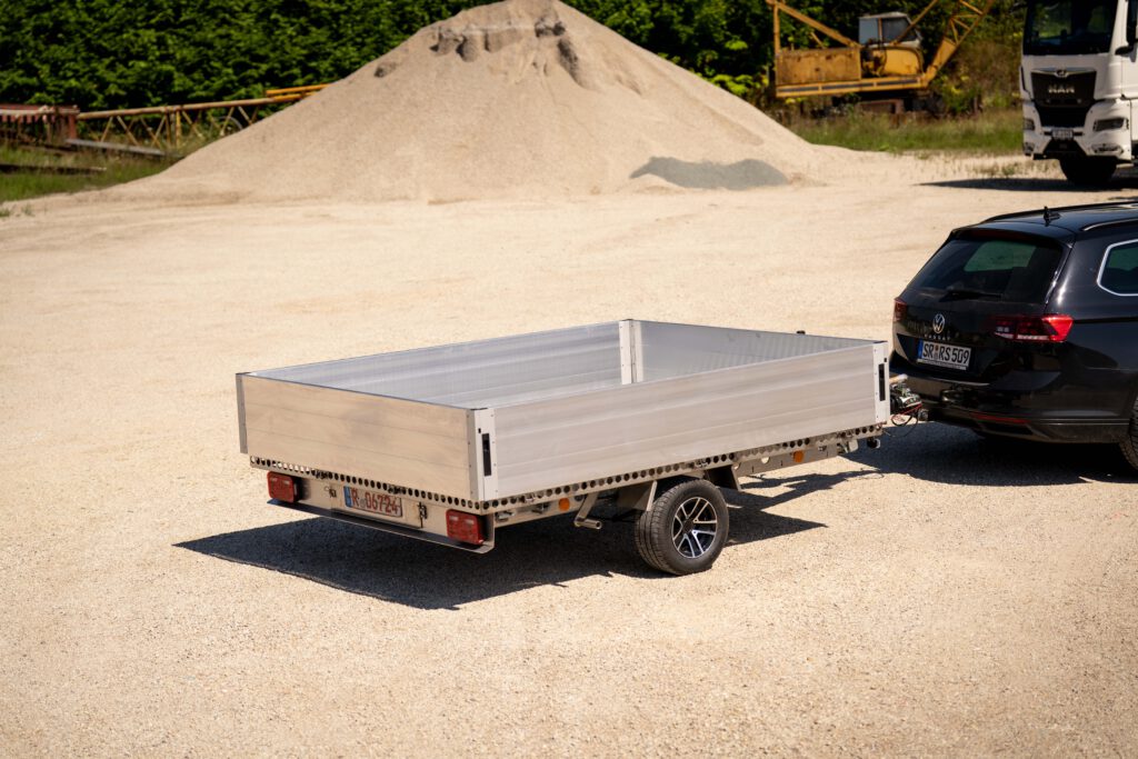 Silberner Anhänger mit Bordwänden vor einem Sandhaufen