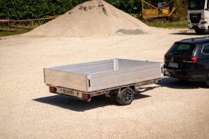 Silberner Anhänger mit Bordwänden vor einem Sandhaufen