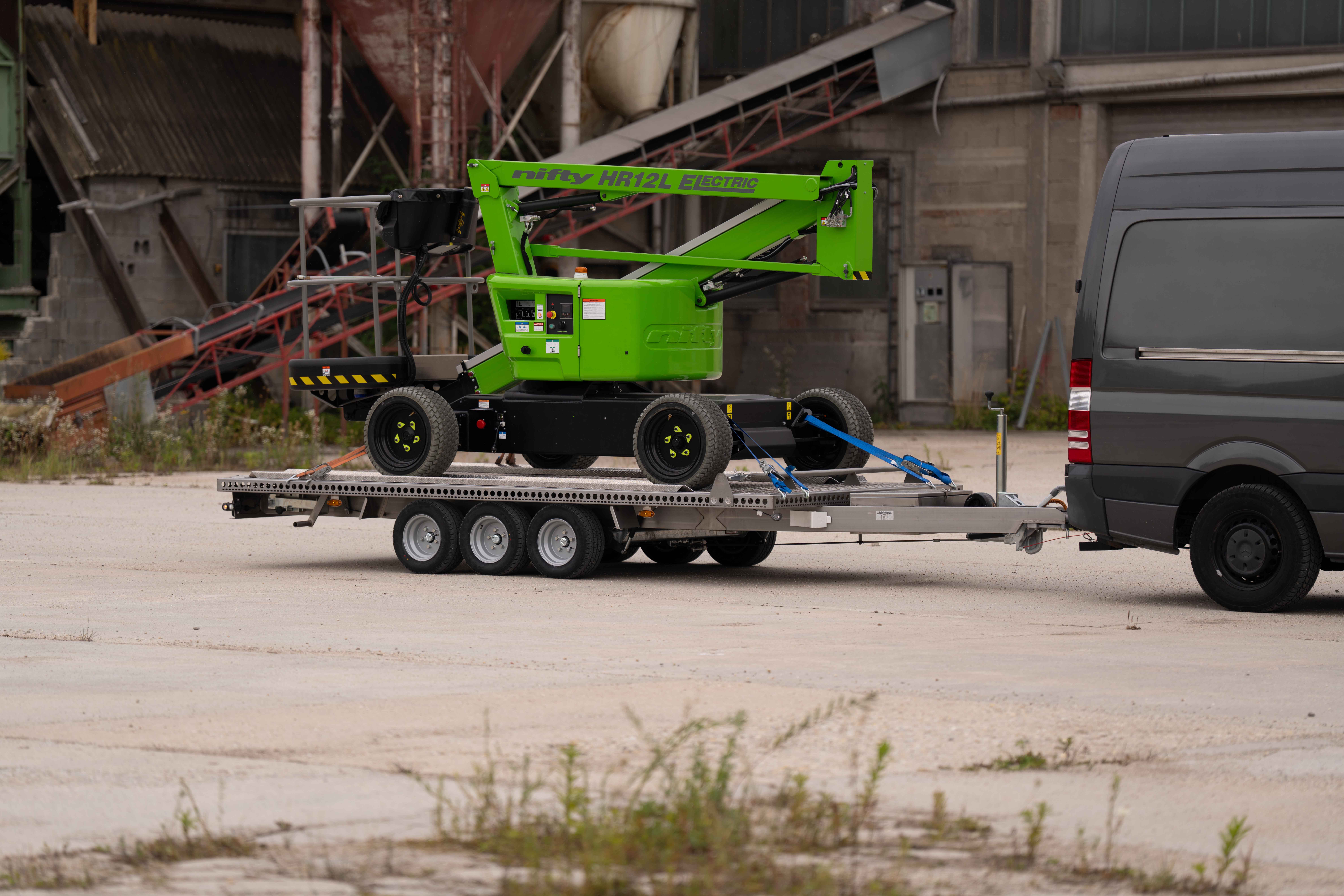Anhänger aus Edelstahl mit einer grünen NIFTY Hebebühne auf einem alten Industriegelände