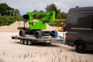 Anhänger aus Edelstahl mit einer grünen NIFTY Hebebühne auf einer Kiesfläche