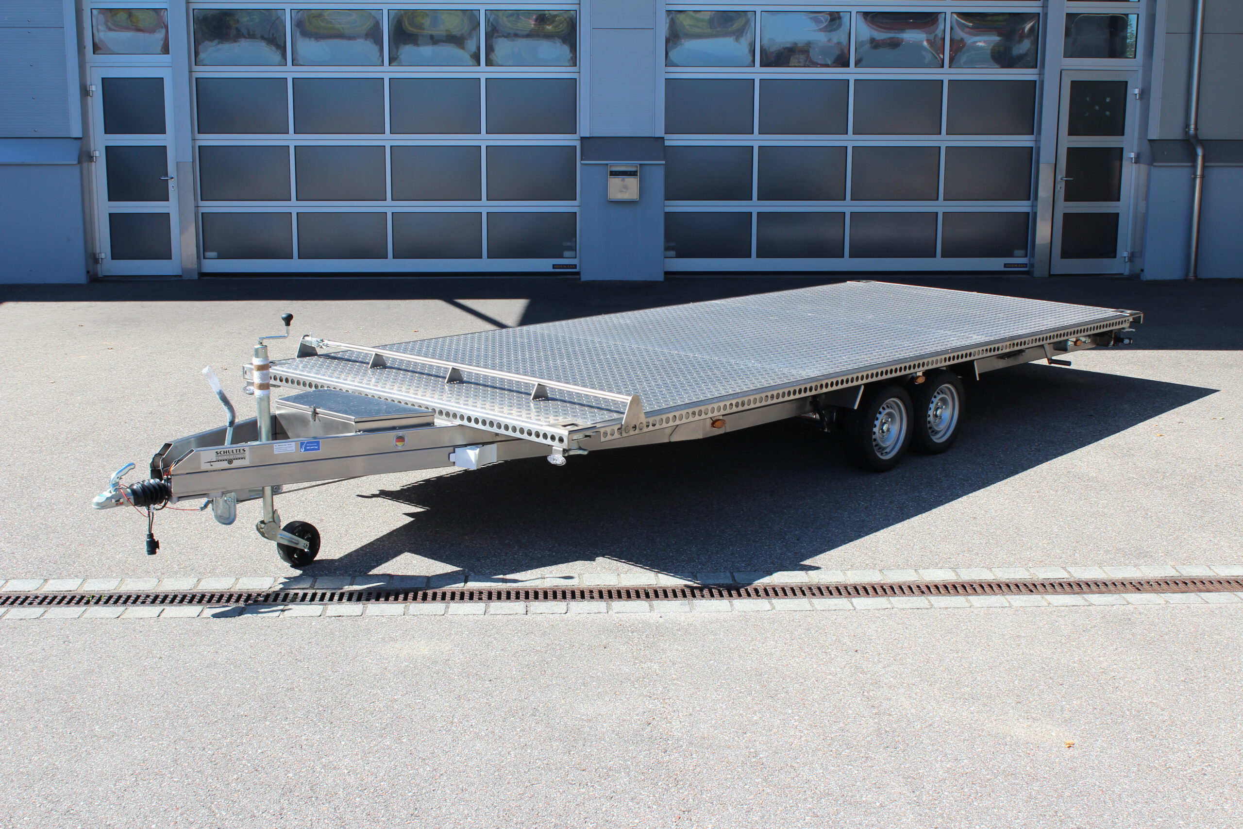 UA600 Container1 Edelstahl Plattform Anhänger mit Twistlock aufnahmen an den 4 Ecken zum Befestigen eines Übersee-Containers. Containertransporter und Plattformanhänger vor einer Halle