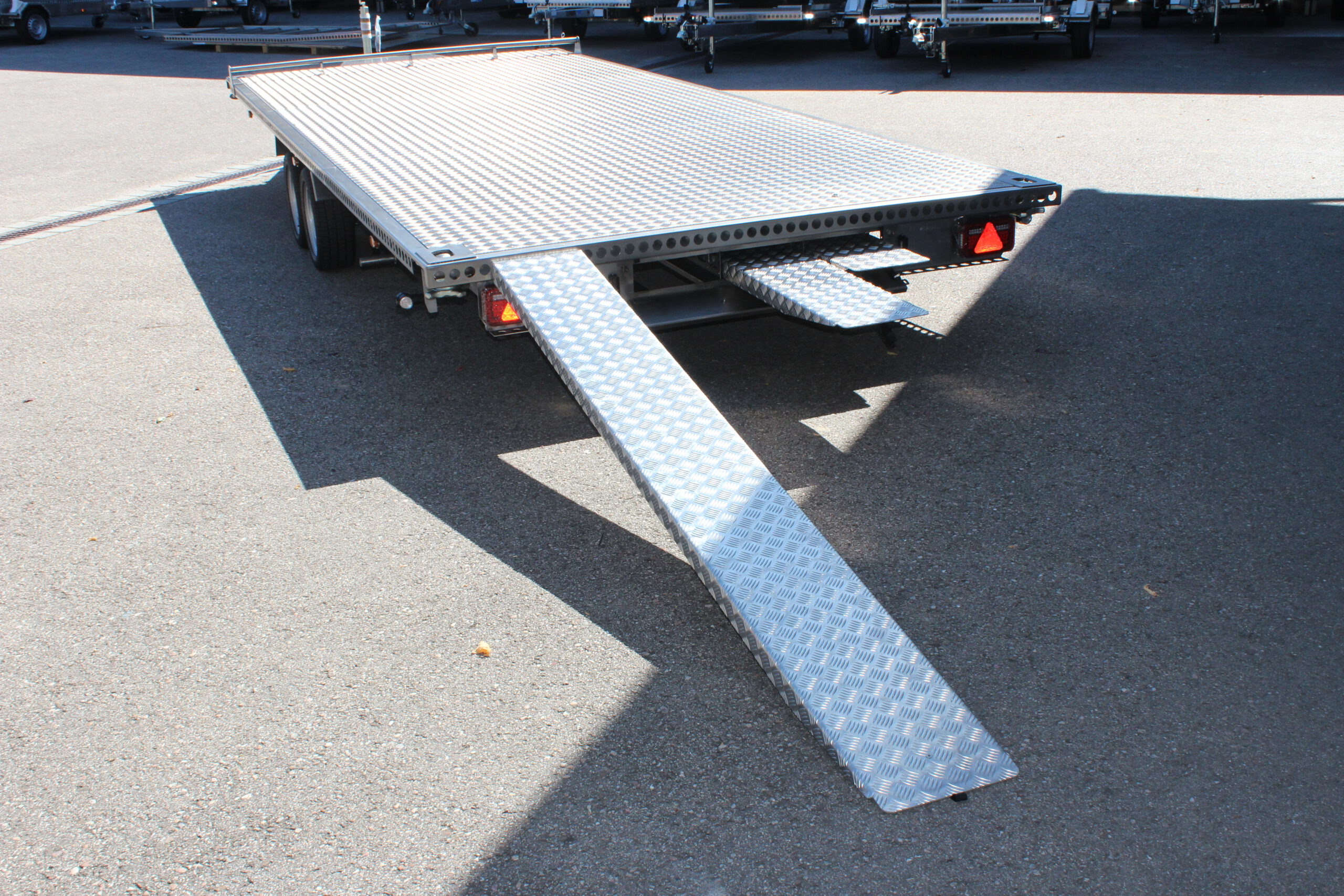 UA600 Container10 Edelstahl Plattform Anhänger mit Twistlock aufnahmen an den 4 Ecken zum Befestigen eines Übersee-Containers. Containertransporter und Plattformanhänger vor einer Halle