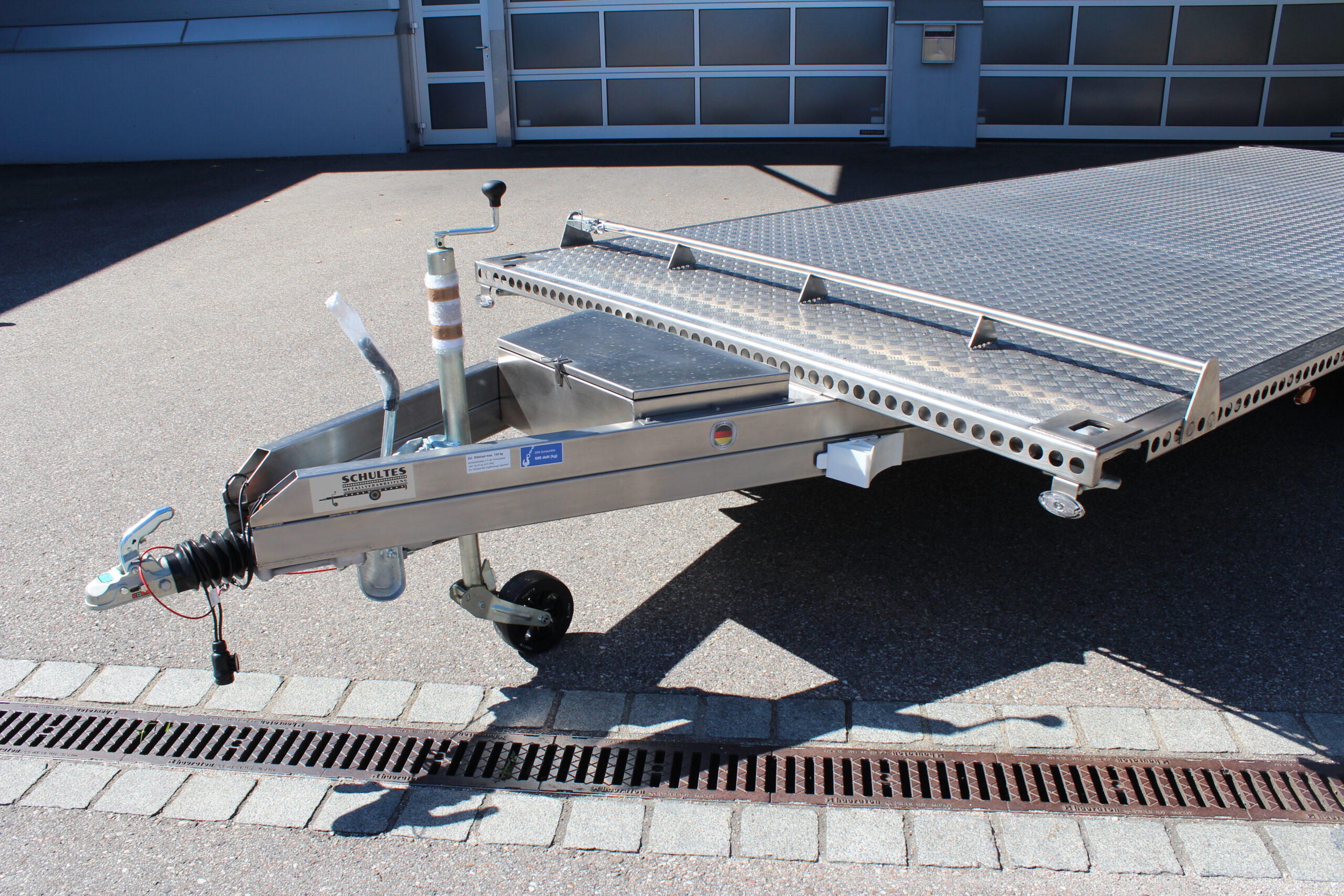 UA600 Container3 Edelstahl Plattform Anhänger mit Twistlock aufnahmen an den 4 Ecken zum Befestigen eines Übersee-Containers. Containertransporter und Plattformanhänger vor einer Halle