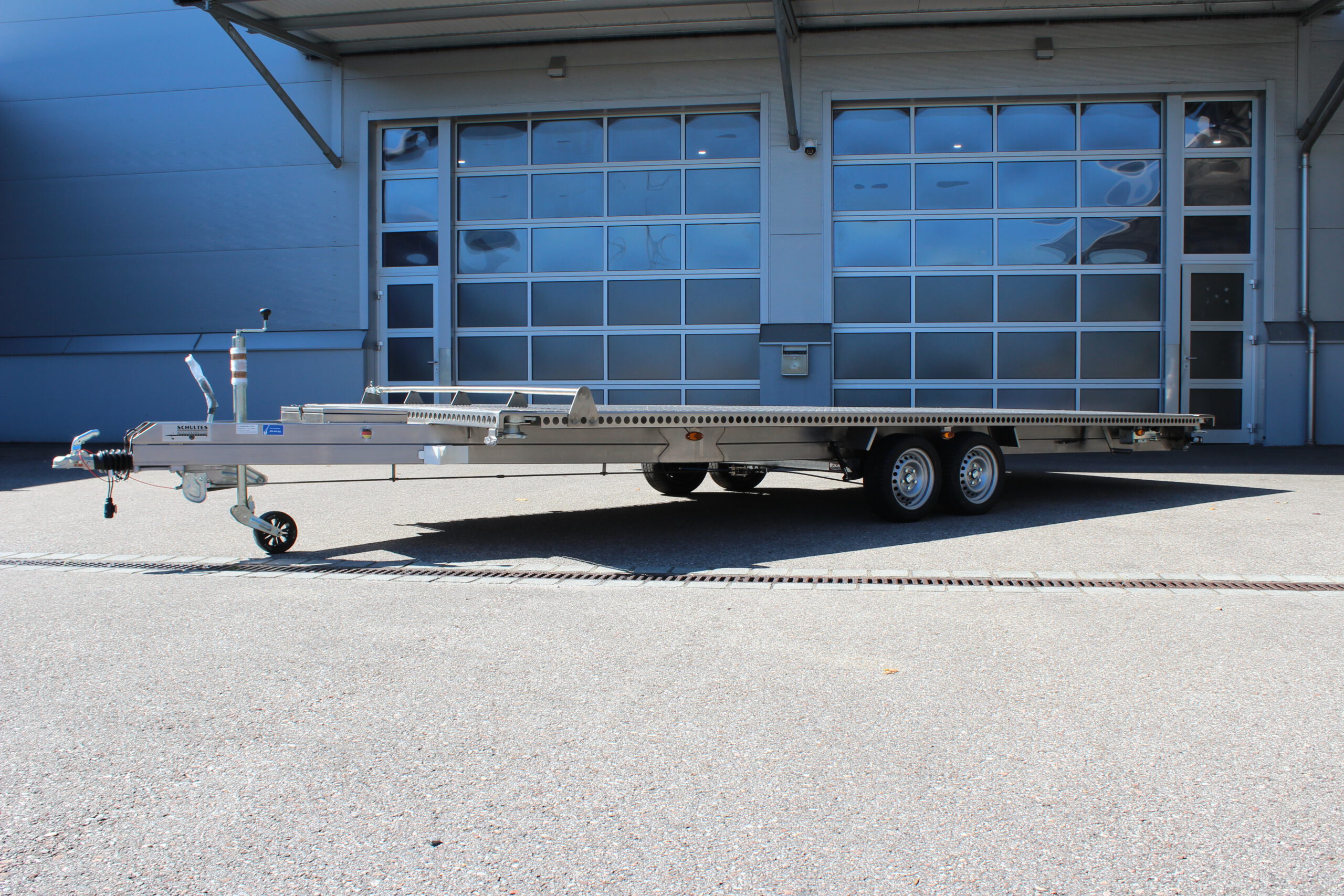 UA600 Container4 Edelstahl Plattform Anhänger mit Twistlock aufnahmen an den 4 Ecken zum Befestigen eines Übersee-Containers. Containertransporter und Plattformanhänger vor einer Halle
