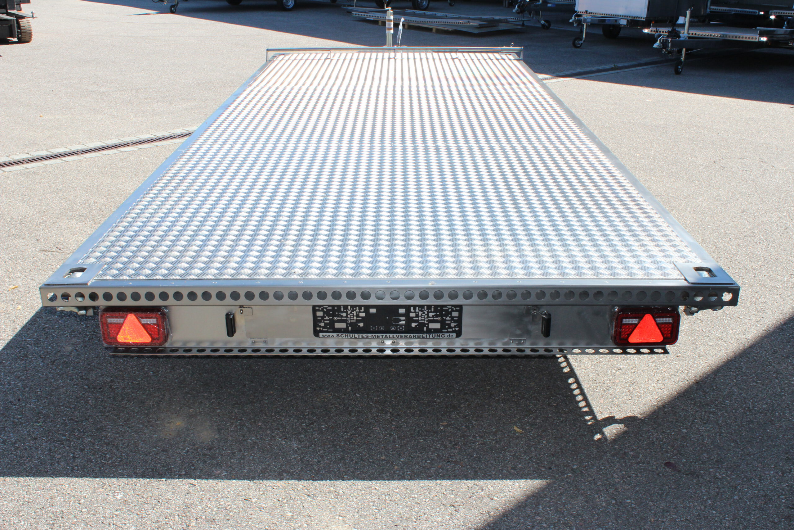 UA600 Container6 Edelstahl Plattform Anhänger mit Twistlock aufnahmen an den 4 Ecken zum Befestigen eines Übersee-Containers. Containertransporter und Plattformanhänger vor einer Halle